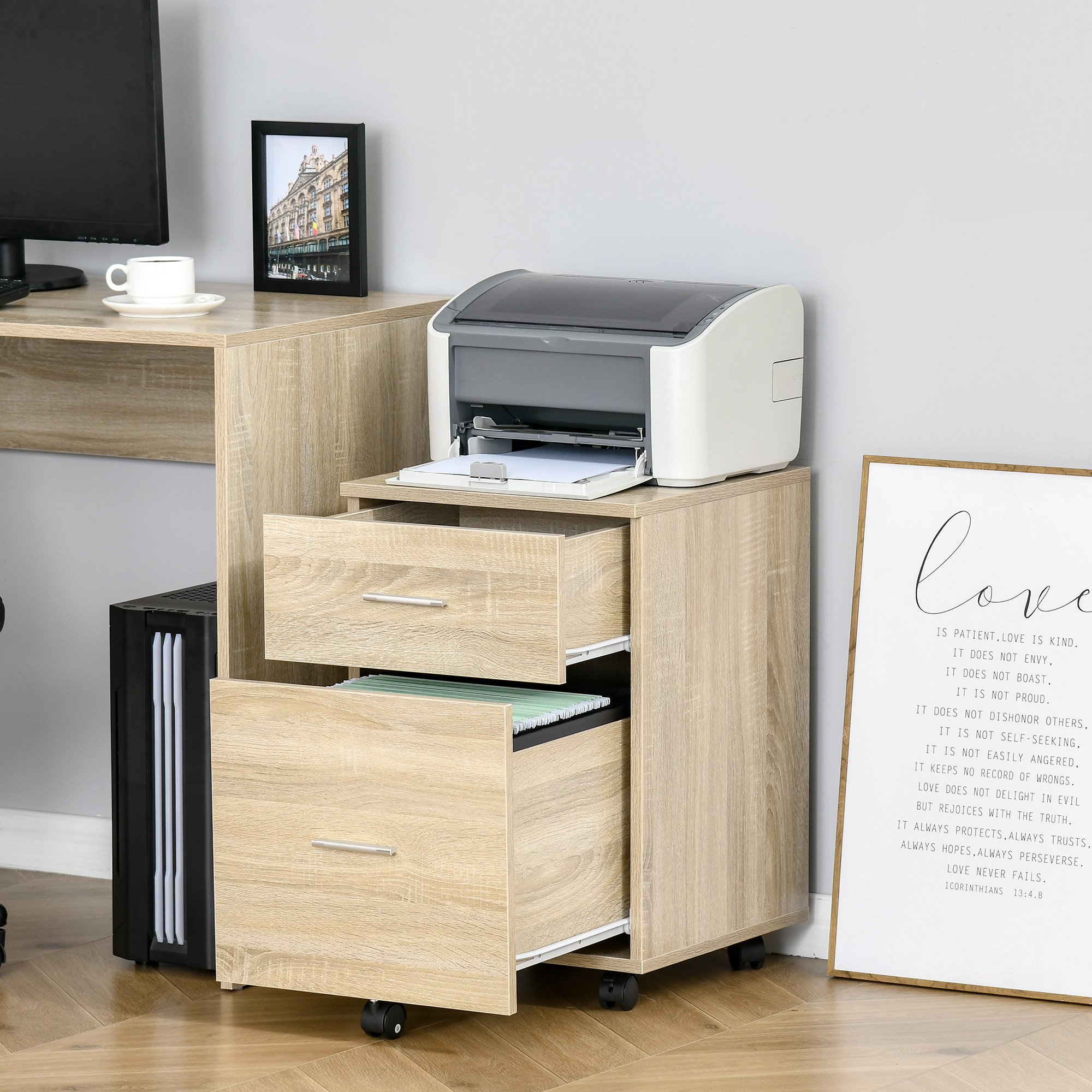 Un archivador de oficina con impresora, ordenador, taza y cuadro.
