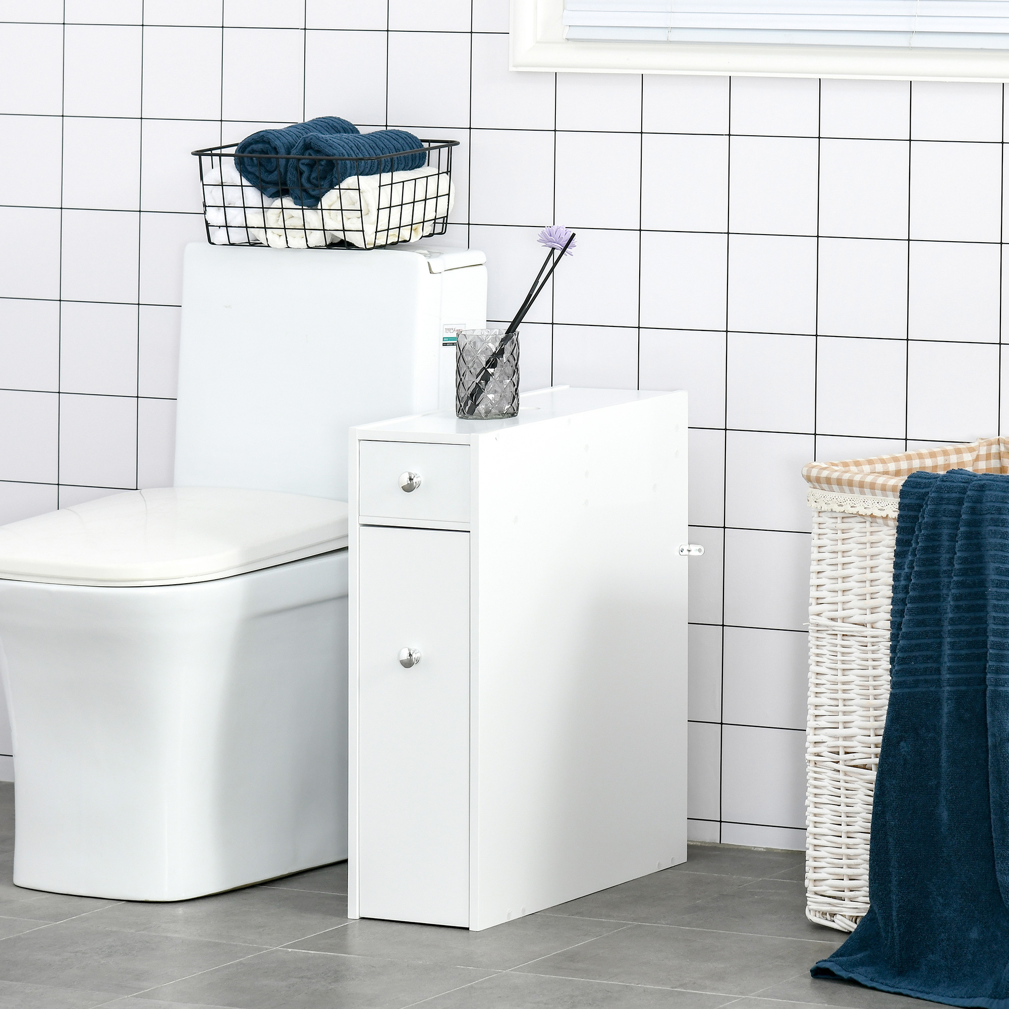 Una escena de baño con inodoro, mueble estrecho, cesta de lavandería y toallas.