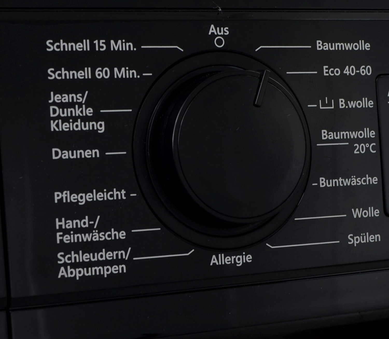 Ein schwarzer Waschmaschinen-Drehregler mit Einstellungen auf Deutsch. Er hat einen zentralen Knopf.