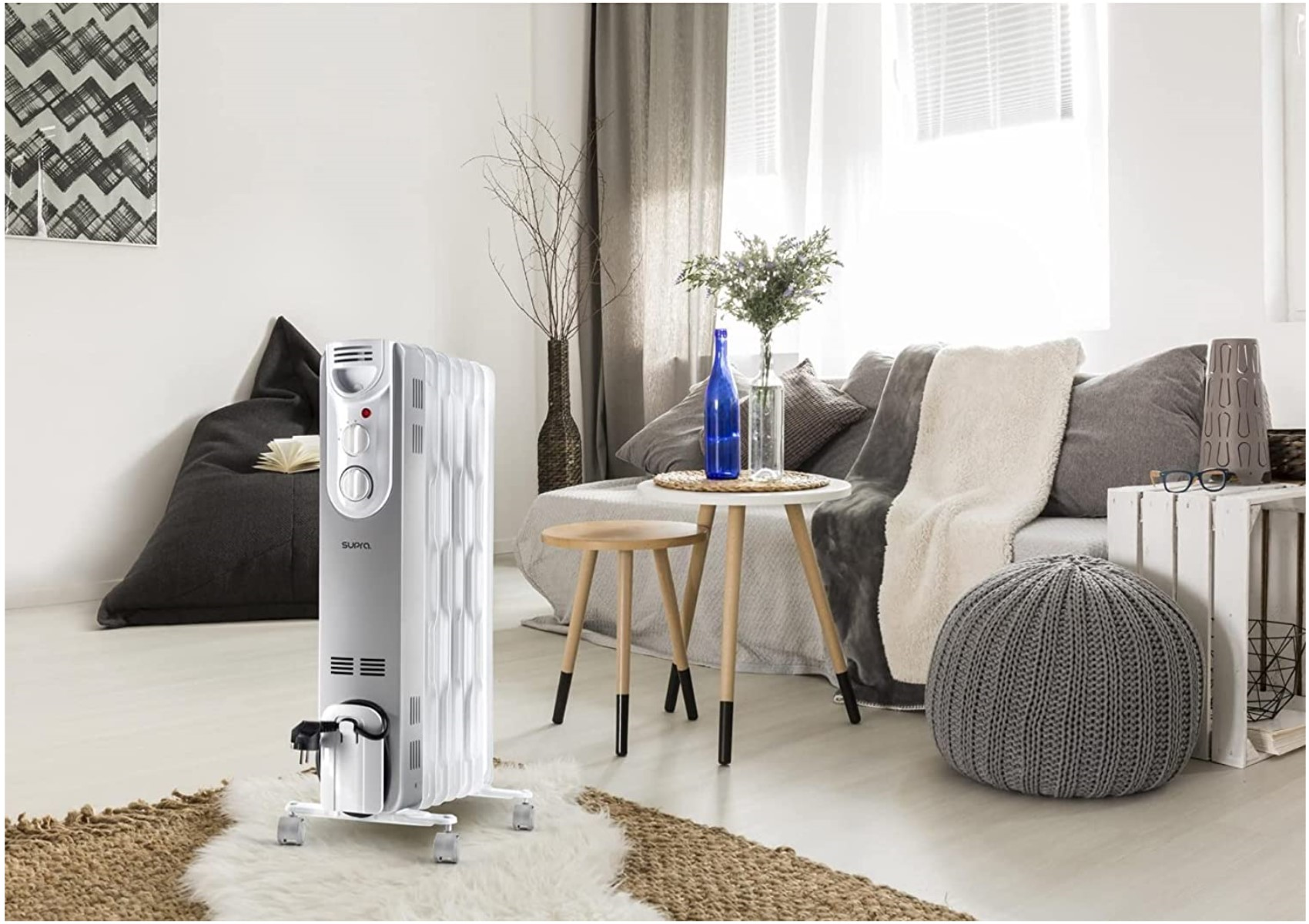 Ein Wohnzimmer mit einem weißen Heizkörper, Sofa, Tisch und dekorativen Elementen. Der Raum hat eine helle und gemütliche Atmosphäre.