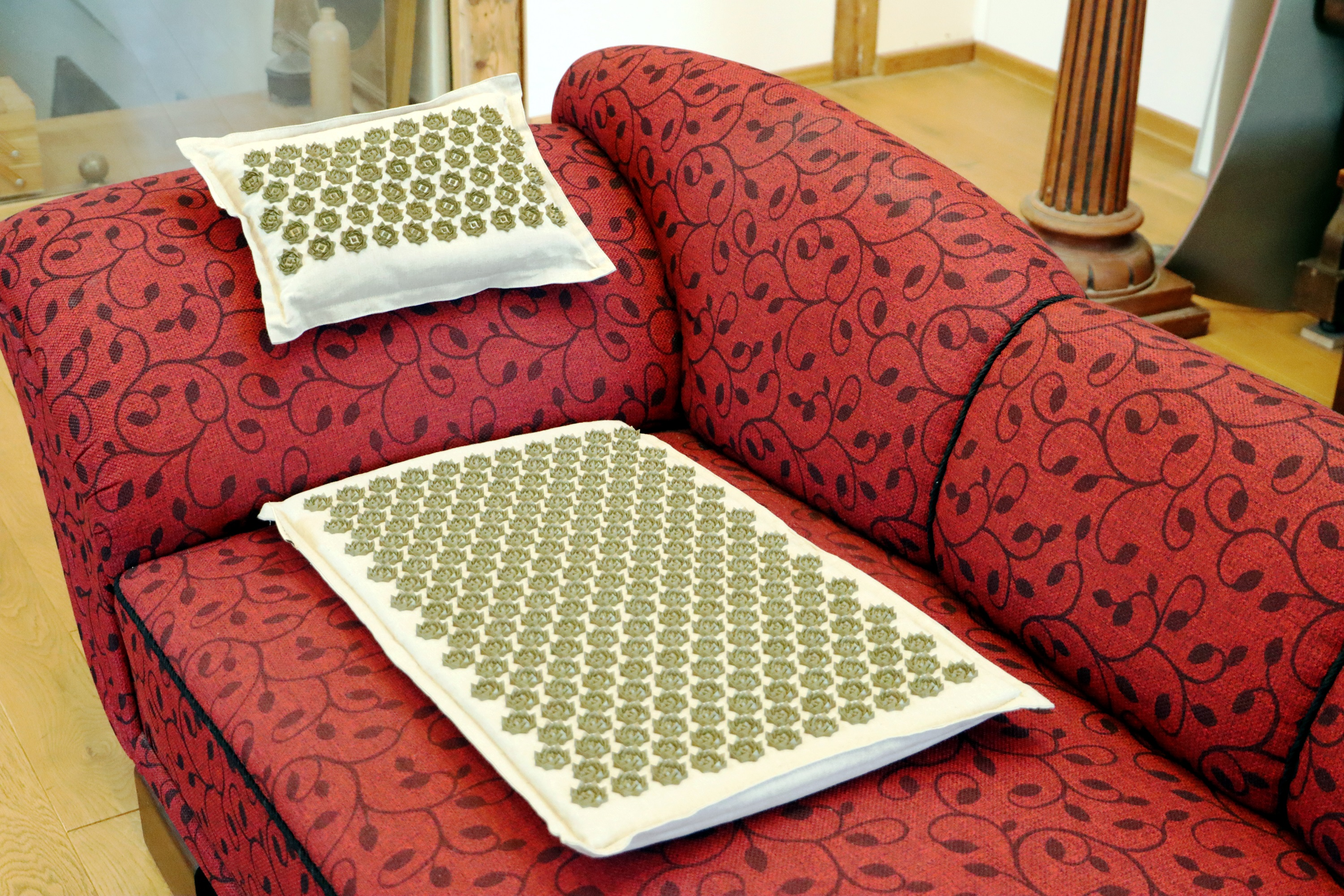 Eine rote Couch mit zwei weißen Kissen mit grünen kreisförmigen Mustern.