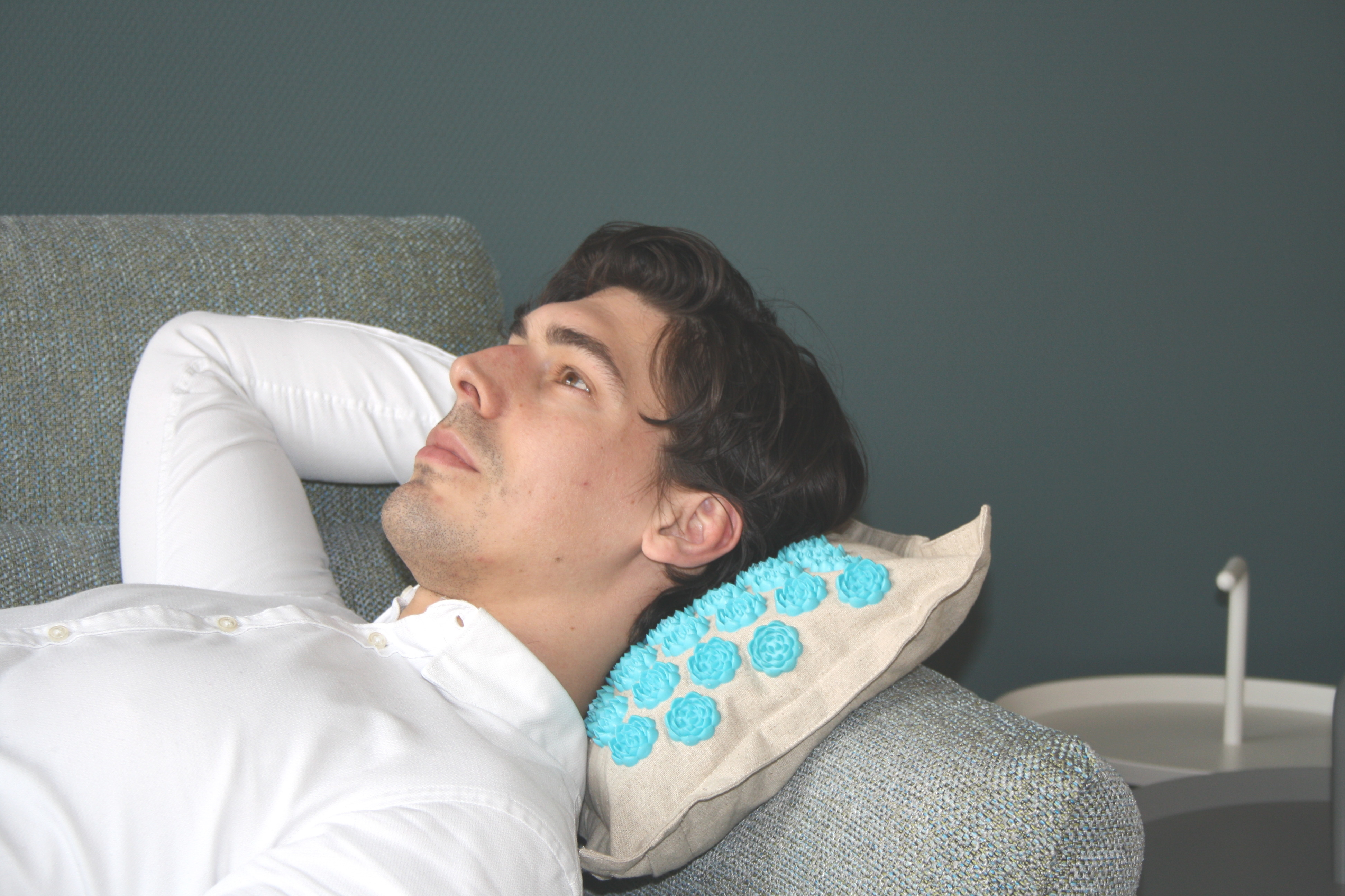 Ein Mann liegt auf einer Couch mit einem Kissen mit blauen blütenartigen Formen.