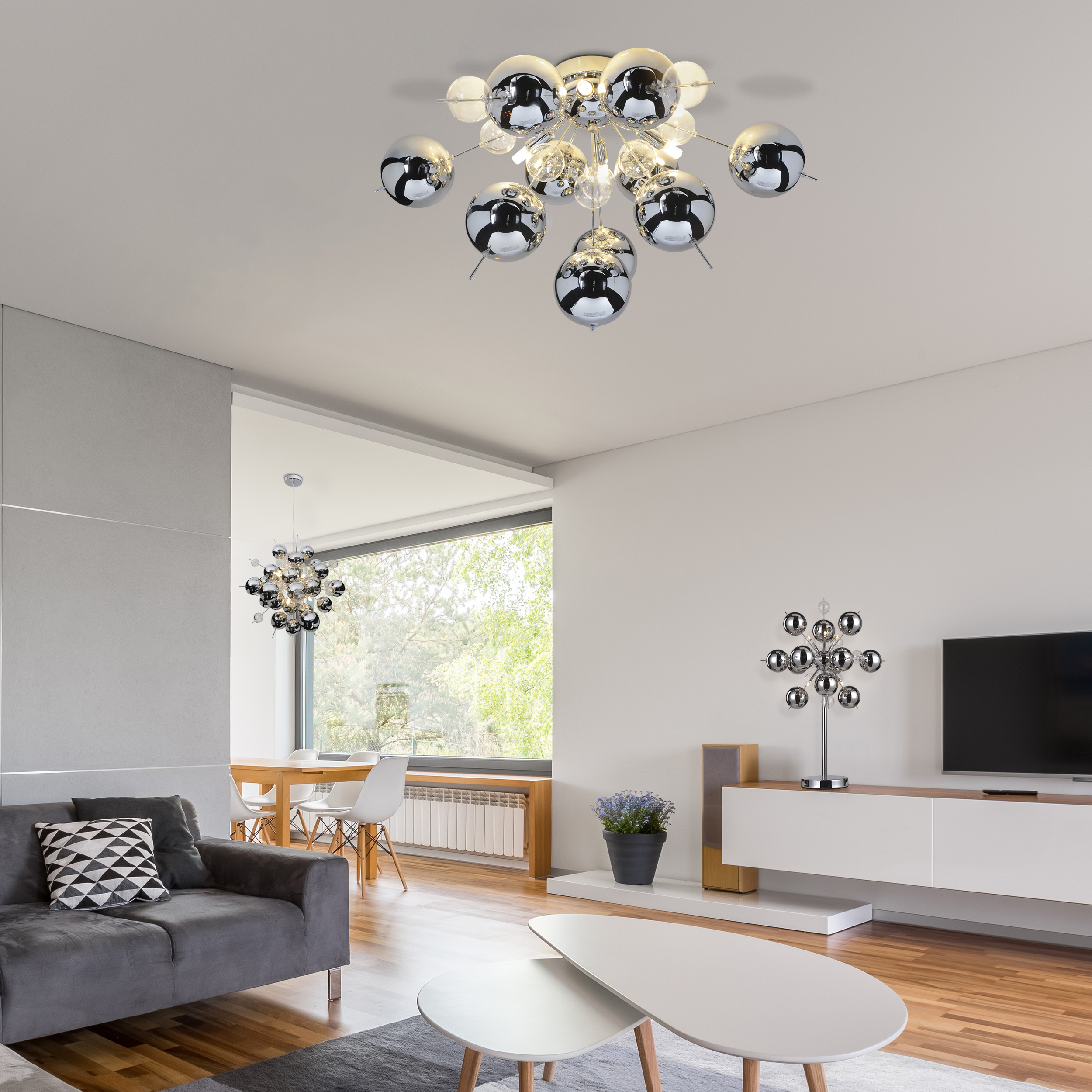 Ein modernes Wohnzimmer mit Deckenleuchter und grauem Sofa. Es gibt zwei weiße Couchtische.