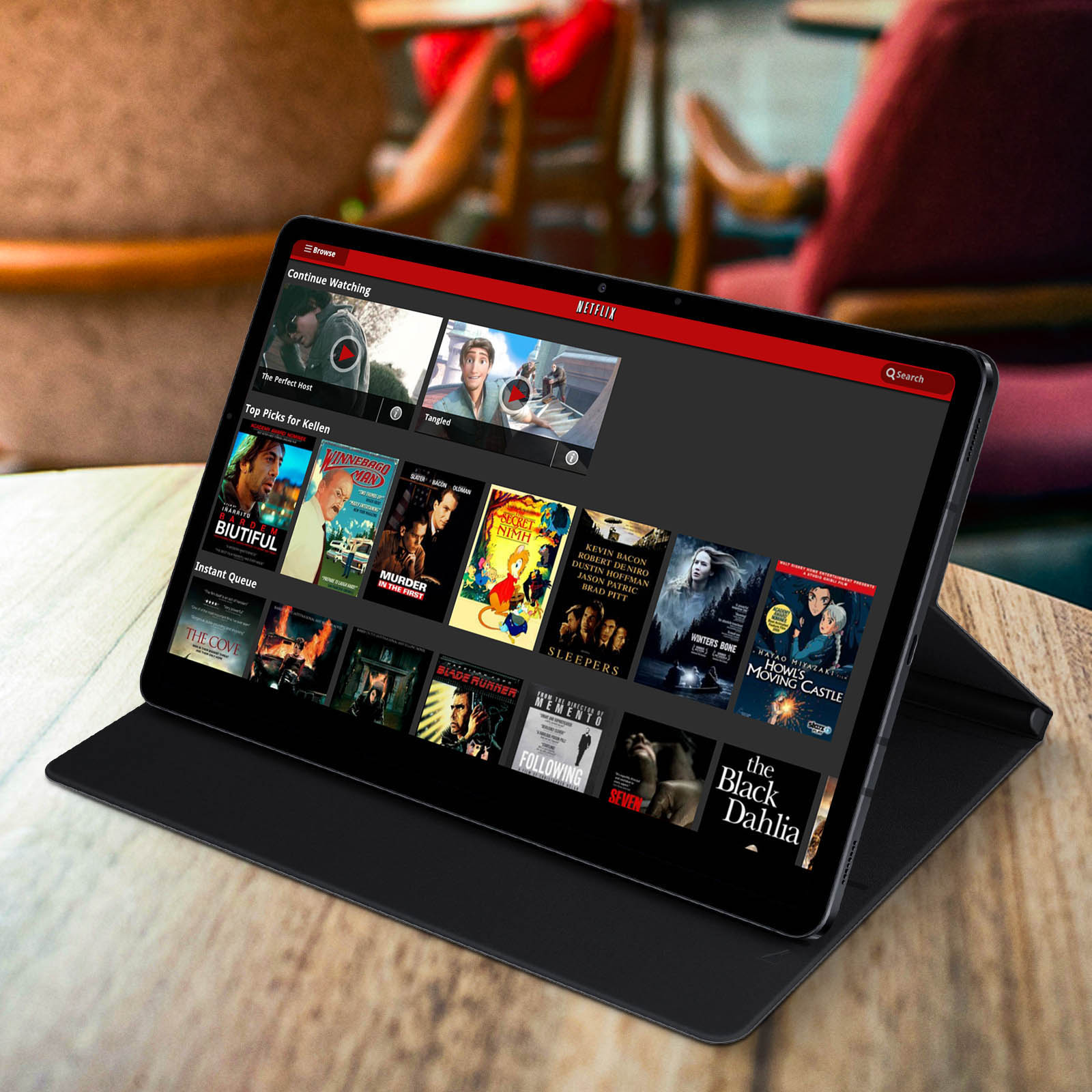 Tableta con interfaz de Netflix abierta, sobre una funda negra en una mesa de madera.
