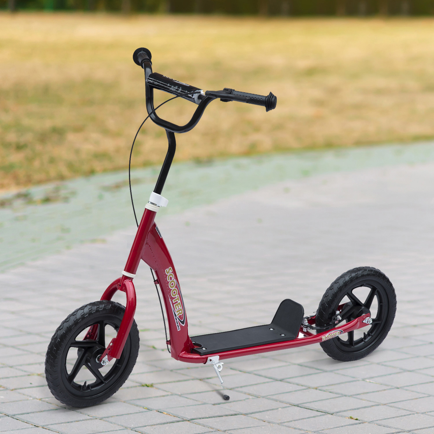 Un patinete rojo sobre una acera gris. Tiene neumáticos y manillar negros, y un reposapiés.