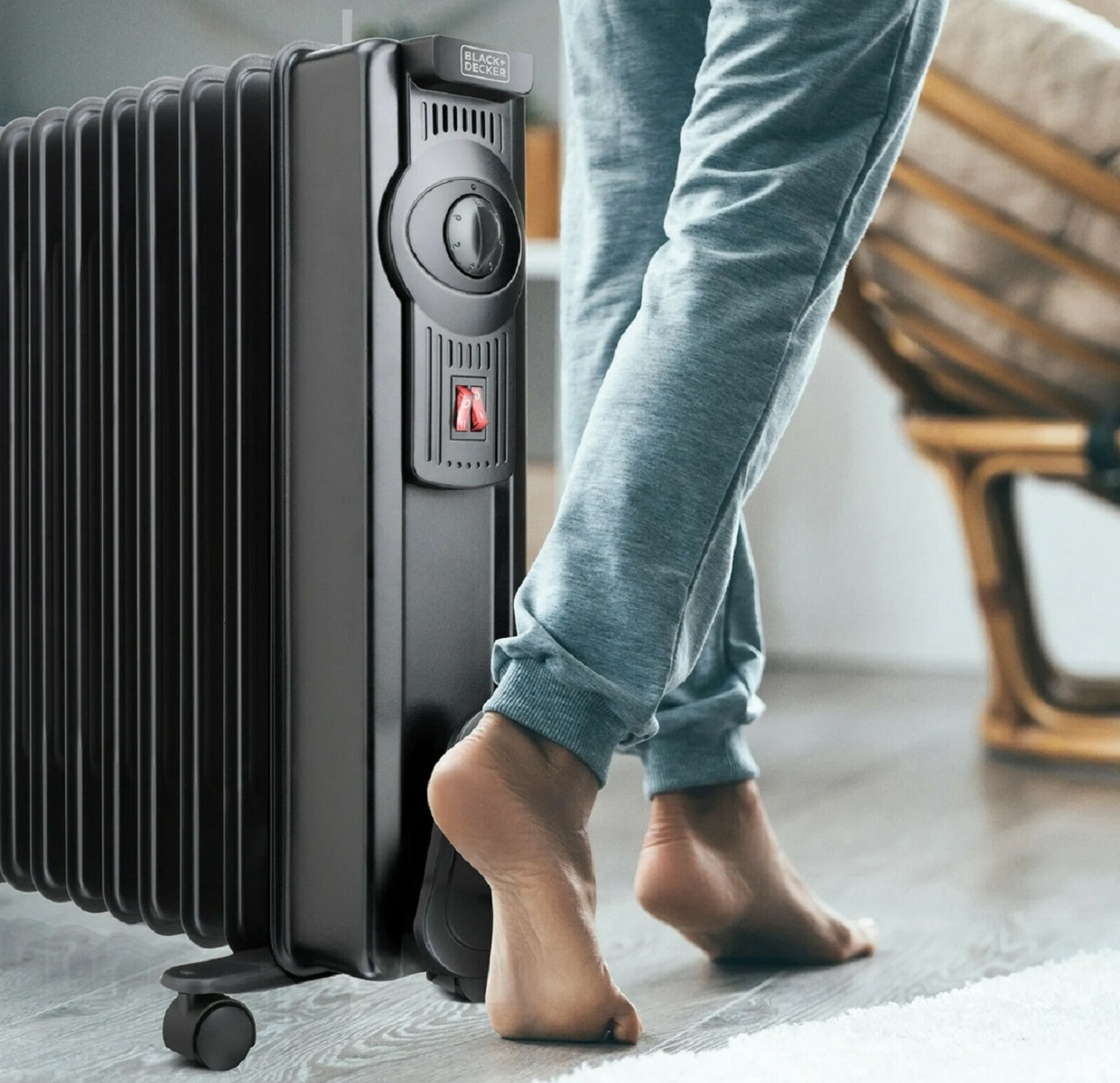 Osoba stojąca obok czarnego grzejnika olejowego.