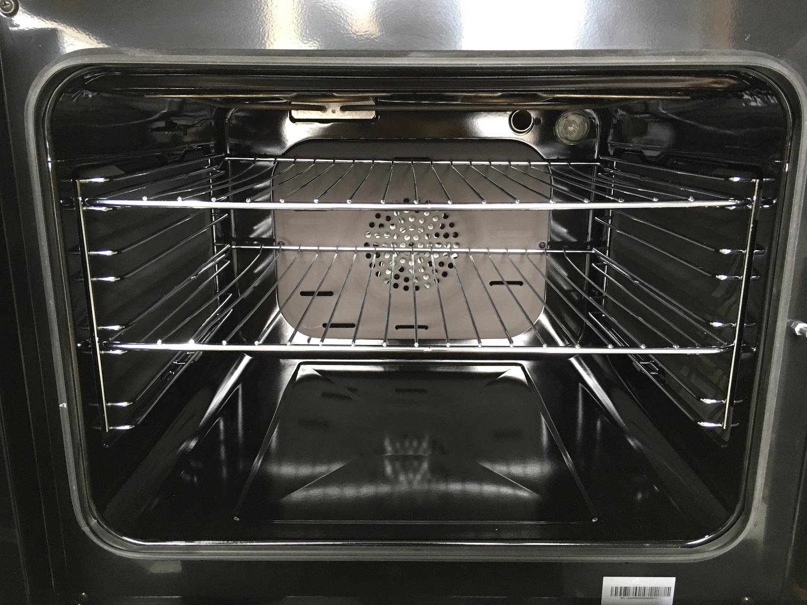 Interior de un horno, mostrando rejillas, un ventilador y las paredes internas.