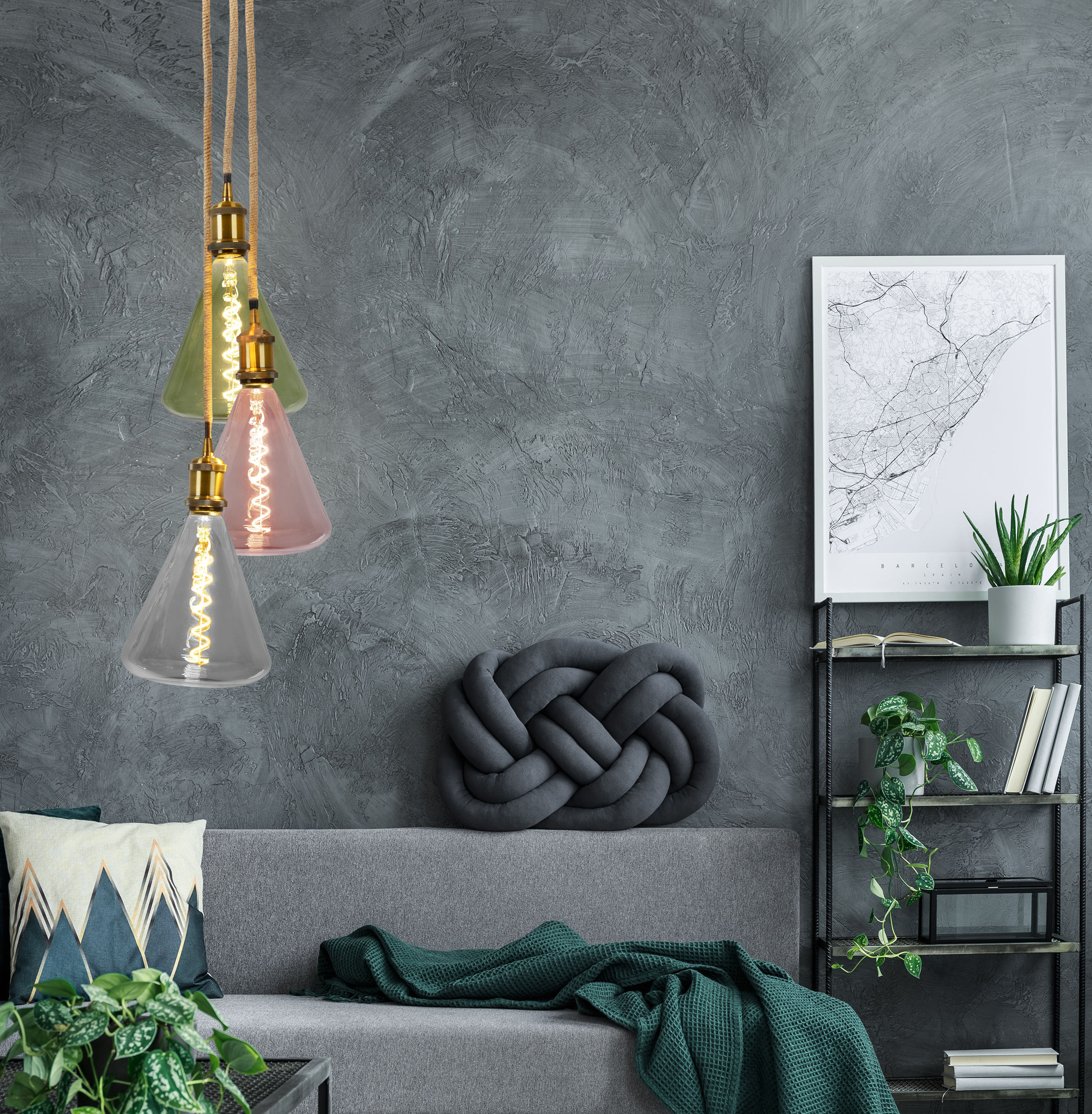 Drei Glühbirnen, verschiedene Farben, hängen an einer grauen Wand. Hintergrund: Sofa, Karte, Dekorationen.