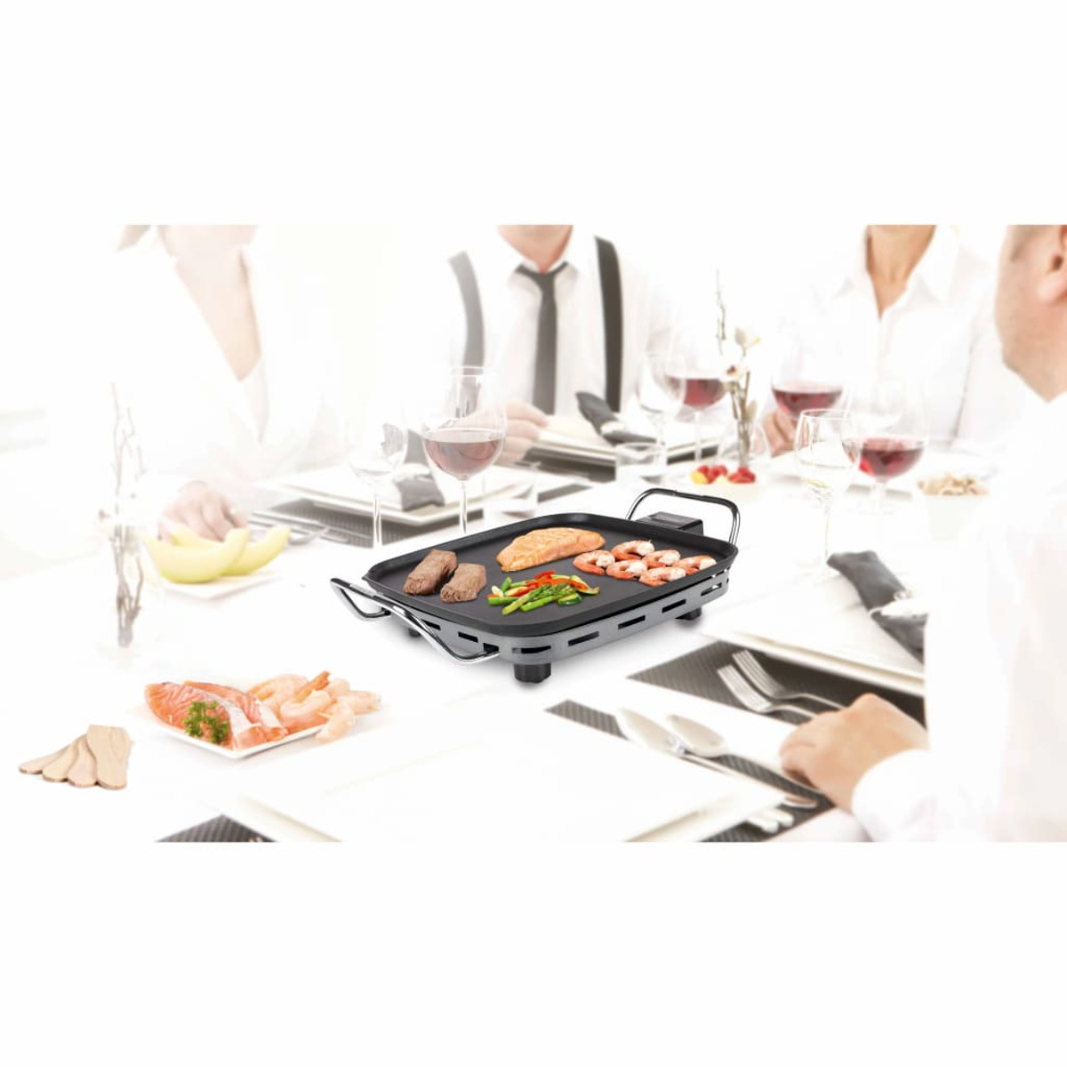 Personas alrededor de una mesa con comida en una parrilla. Algo de comida en la mesa.