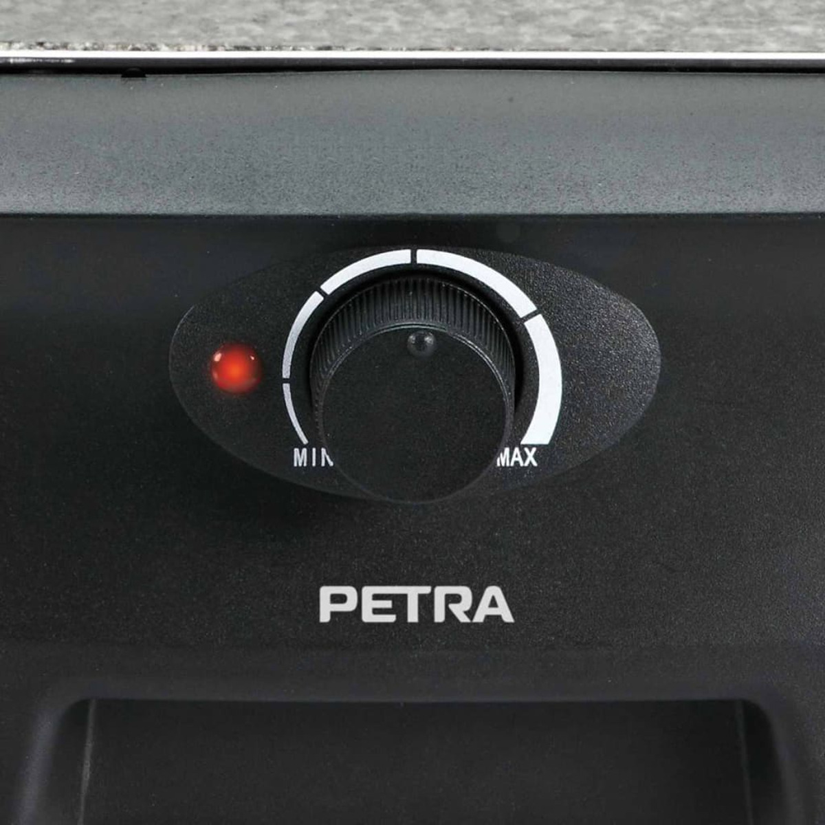 Zbliżenie czarnego pokrętła sterowania dla urządzenia 'PETRA' z czerwoną lampką. Jest napisane 'MIN' i 'MAX'.