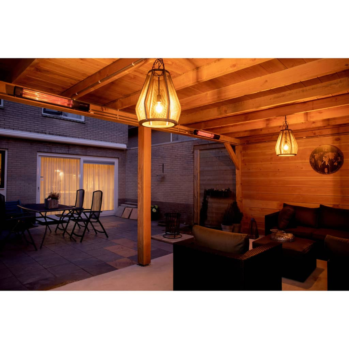 Een terras met een houten pergola, twee hanglampen en tuinmeubelen. Er is een bakstenen muur op de achtergrond.