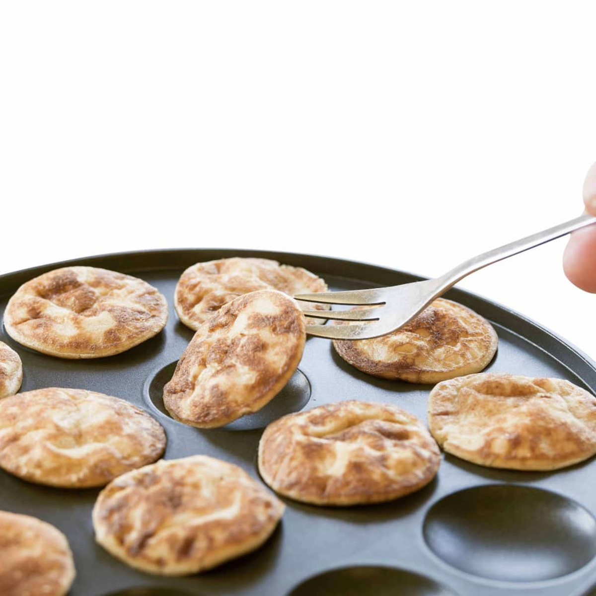 Widelec wyjmuje naleśnik z patelni. W patelni są inne naleśniki.