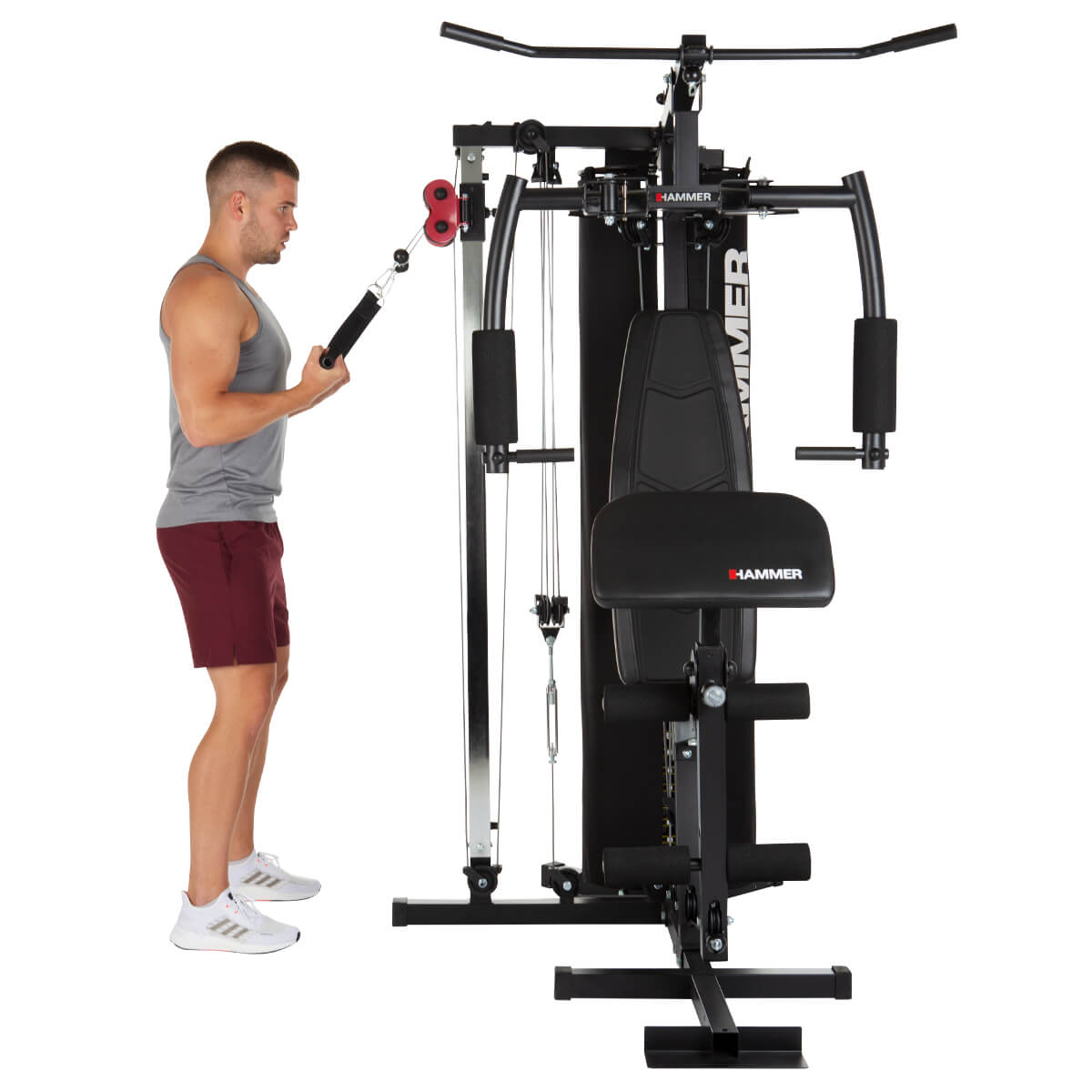 Ein Mann trainiert an einer Multi-Gym-Maschine. Die Maschine ist schwarz und trägt den Markennamen „HAMMER“.