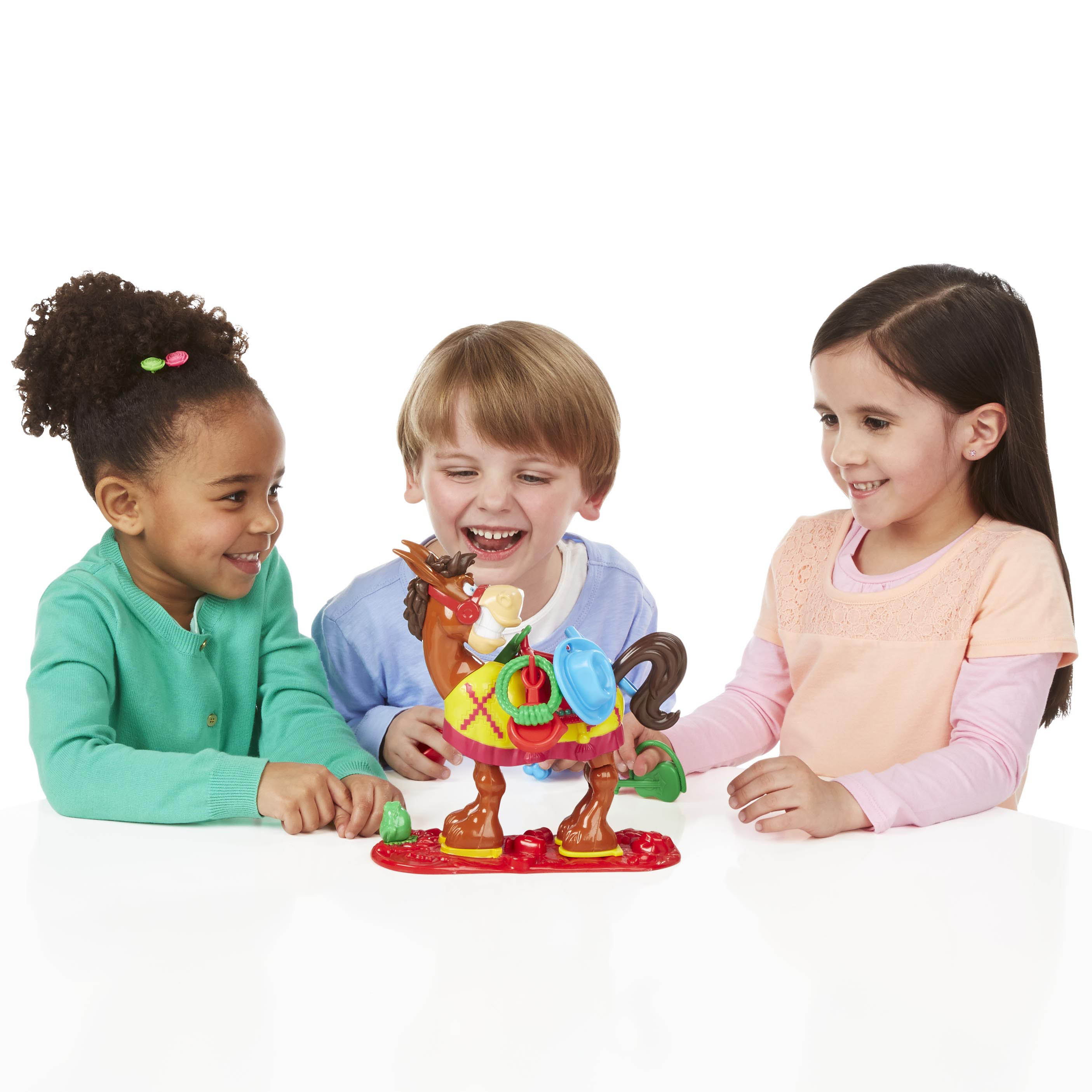Tres niños jugando a un juego de caballos. El caballo es marrón, amarillo y rojo.