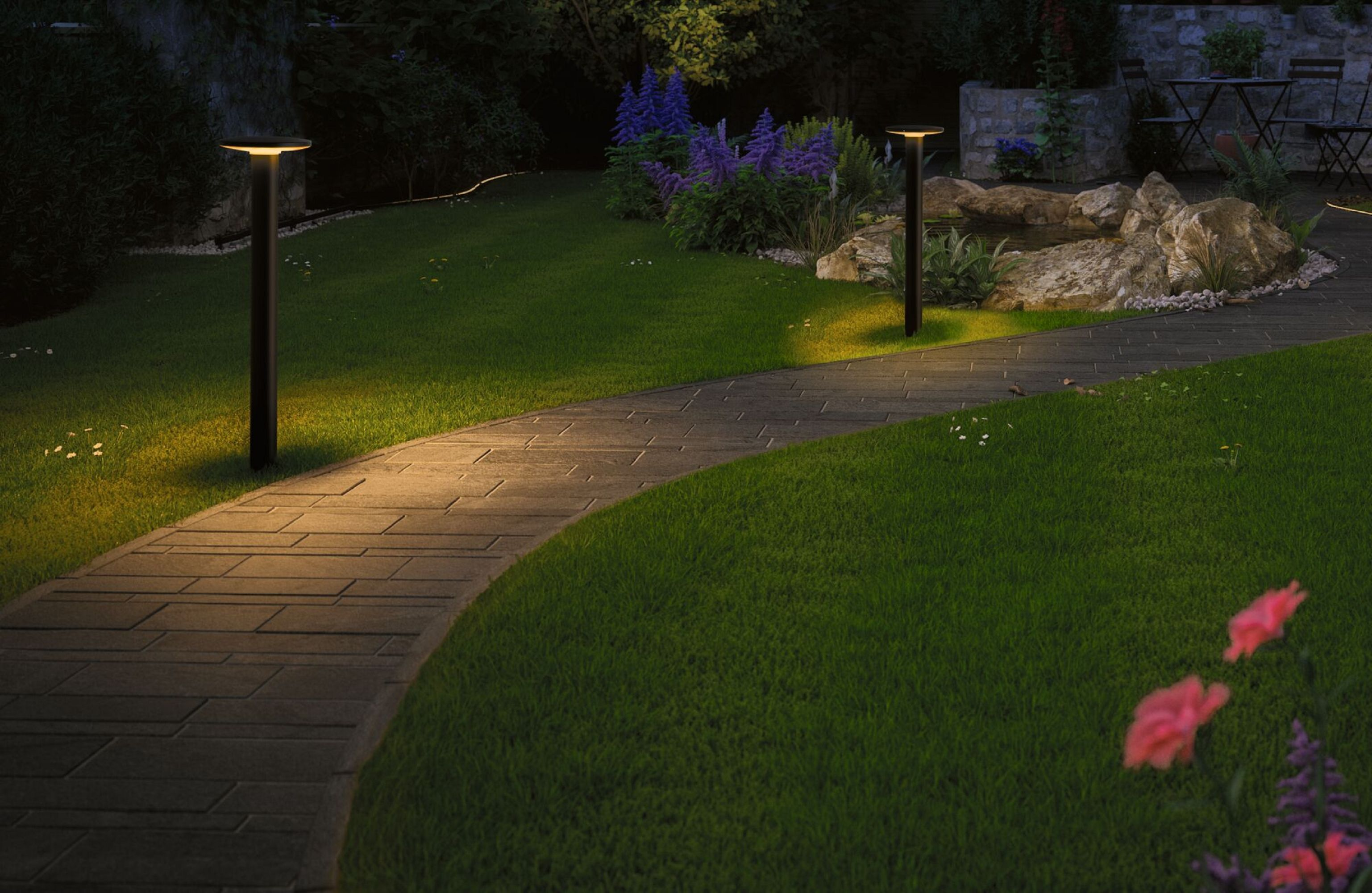 Ein Gartenweg bei Nacht mit zwei beleuchteten Laternen und einem Steinweg.