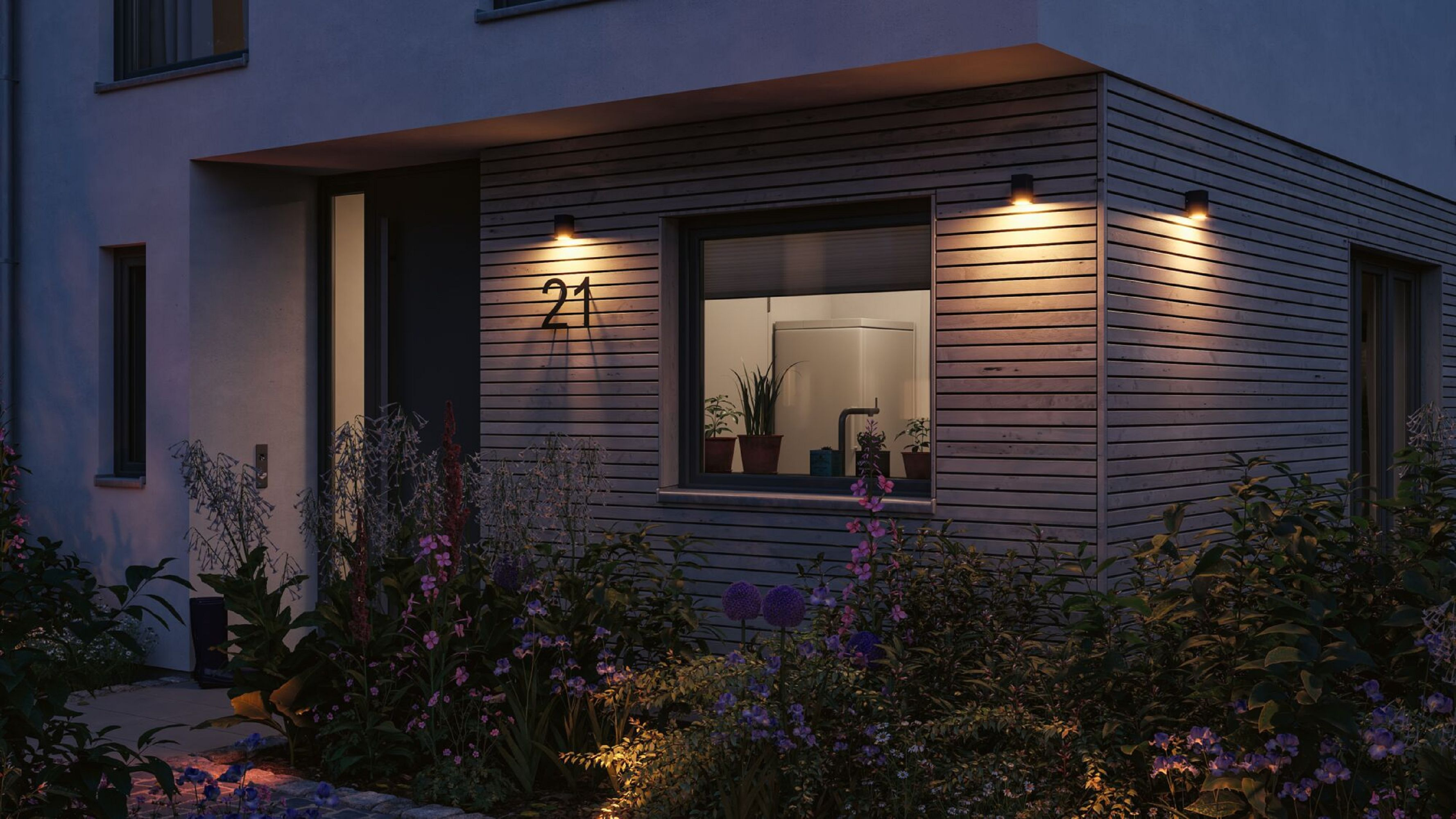 Hausfassade bei Nacht mit Lichtern an und Hausnummer 21.