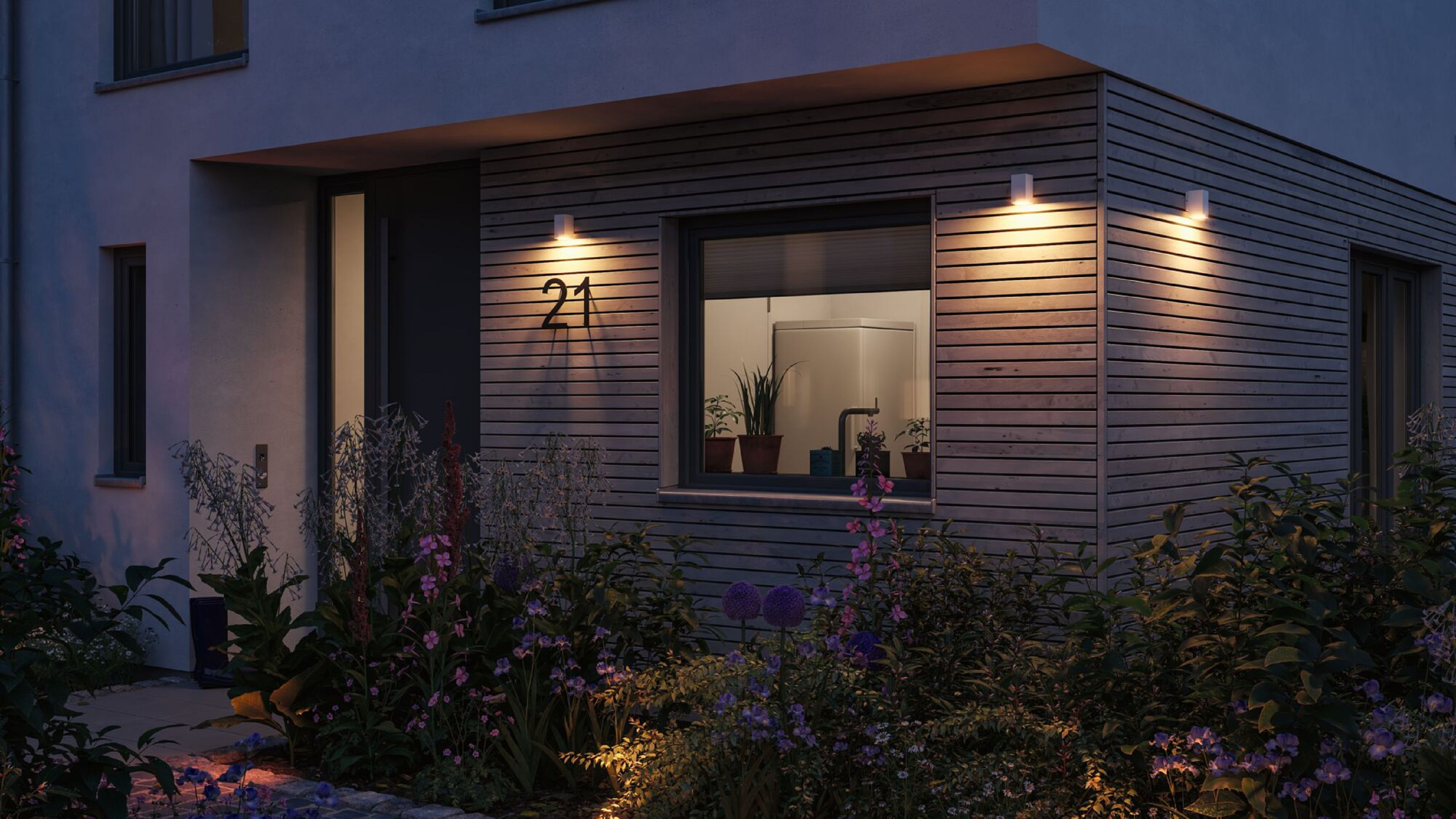 Modernes Haus von außen mit beleuchteten Lichtern und der Nummer 21.