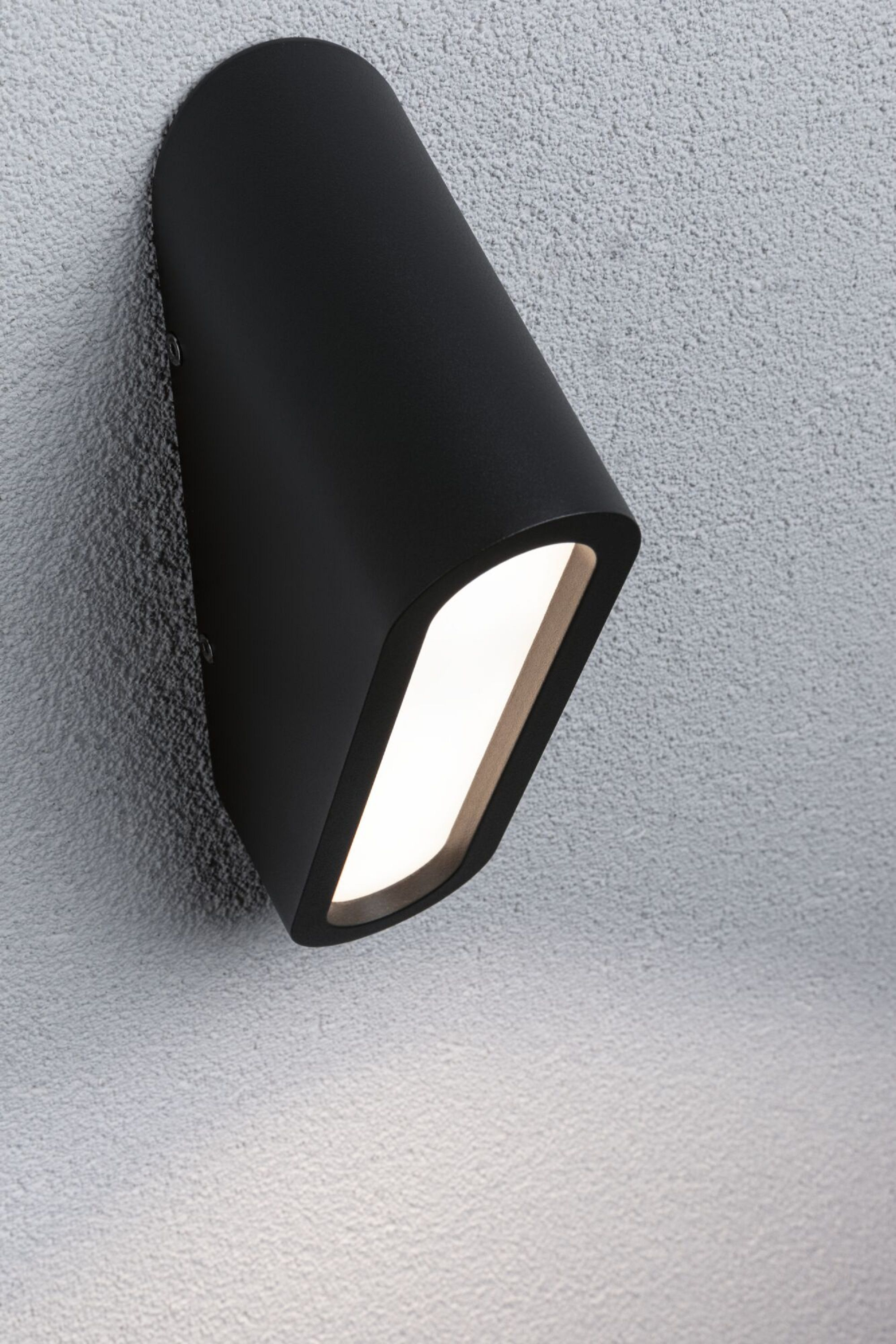 Schwarze Außenwandleuchte. Montiert an einer strukturierten grauen Wand. Weißes Licht emittierend.