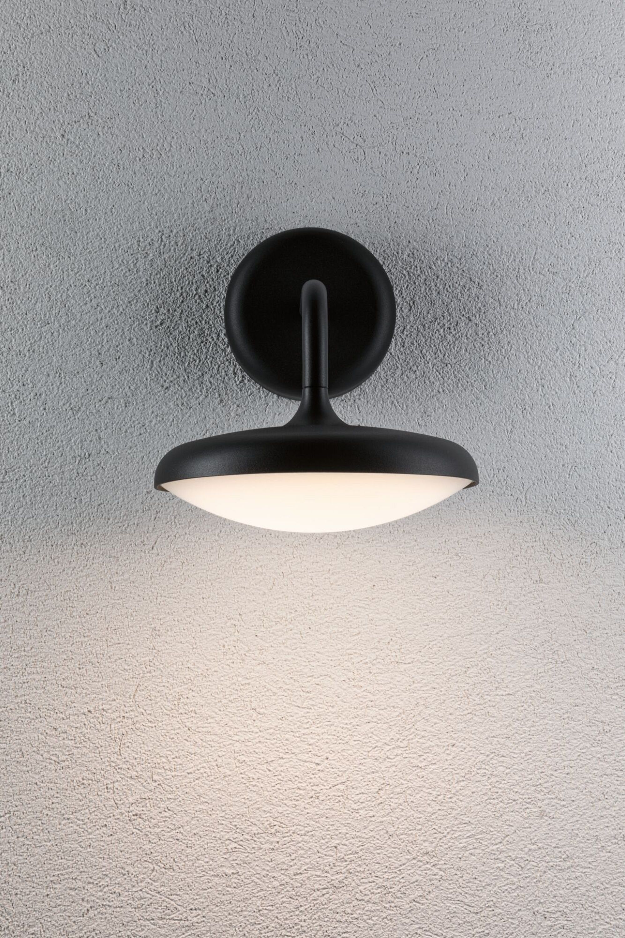 Schwarze Wandleuchte mit kreisförmigem Sockel und scheibenförmigem Licht. Das Licht strahlt nach unten.