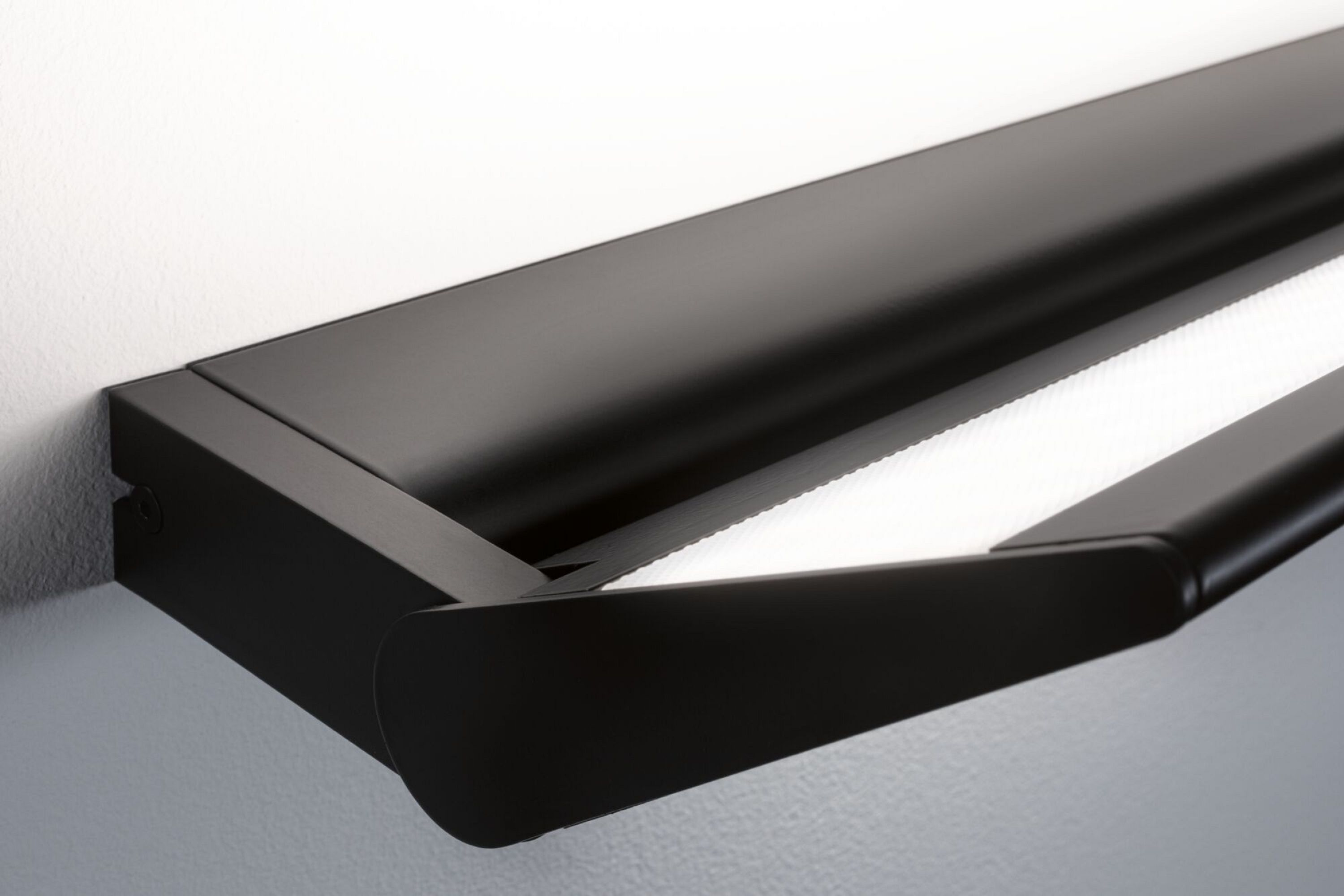 Apparecchio di illuminazione a LED nero, montato a parete, angolato verso il basso con luce bianca brillante.