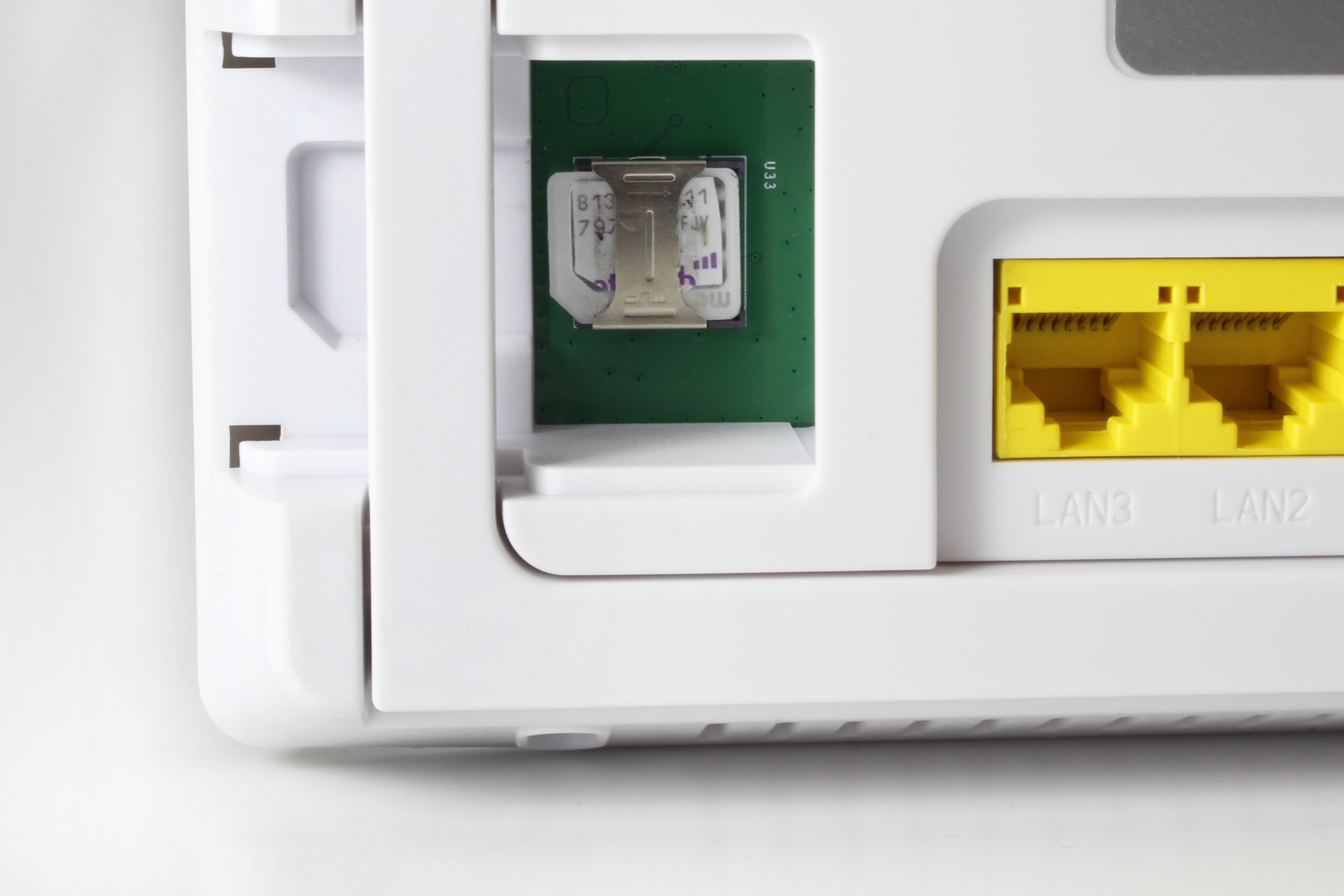 Nahaufnahme eines weißen Routers mit eingelegter SIM-Karte, zwei gelben Netzwerkanschlüssen.