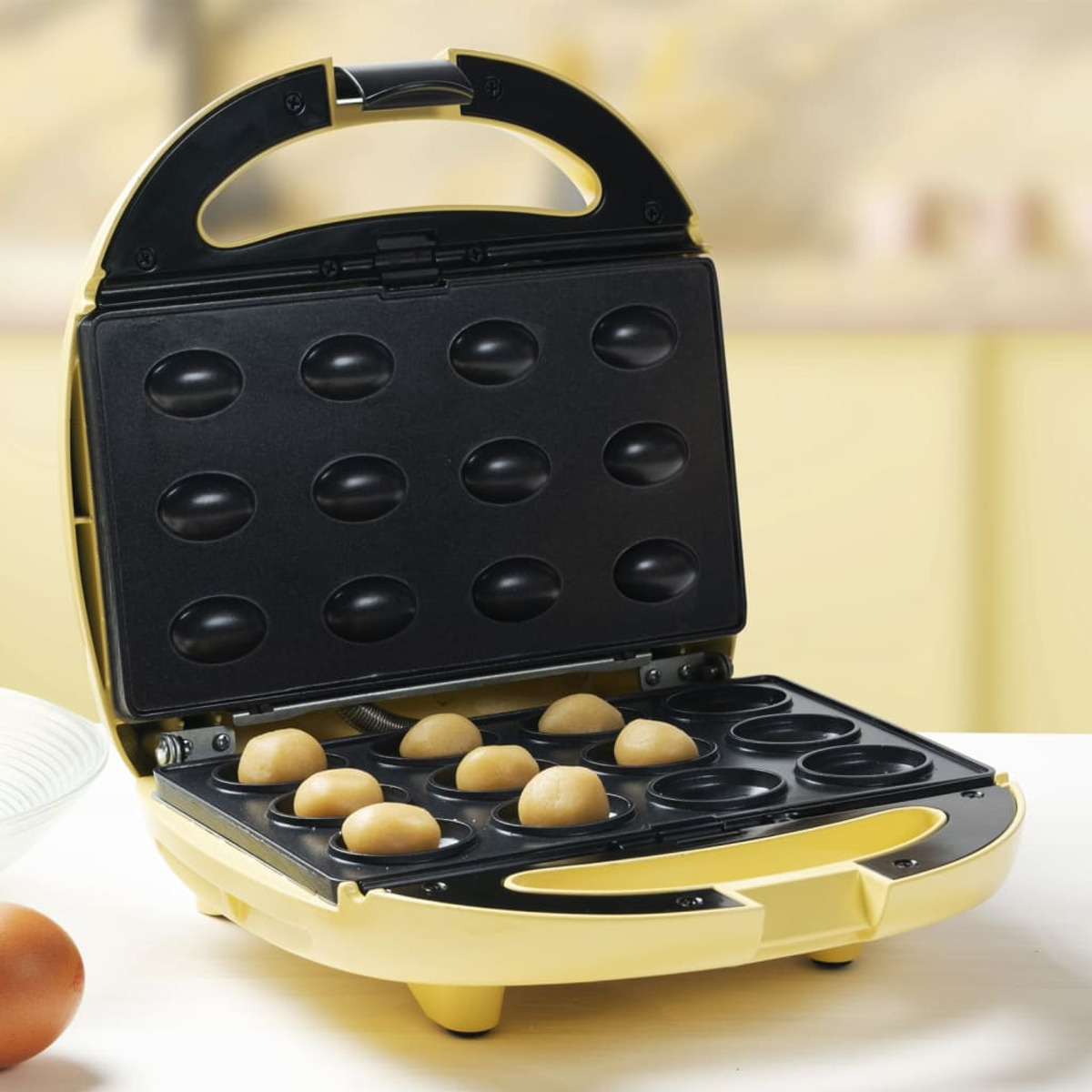 Ein offener gelber Waffeleisen mit gebackenen Waffeln in den Formen, auf weißem Hintergrund.