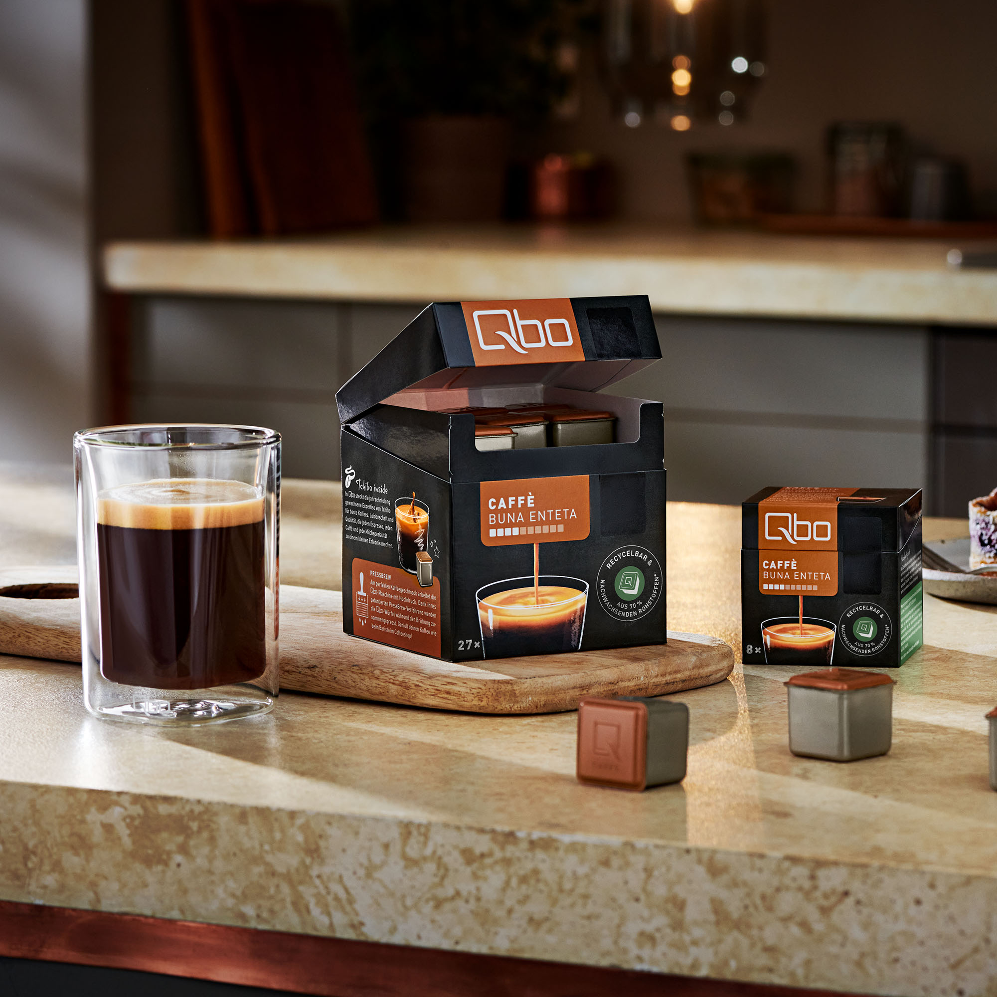 Kaffeepads und eine Tasse Kaffee mit einem Glasbecher. Kaffeepad-Box auf Holzoberfläche.