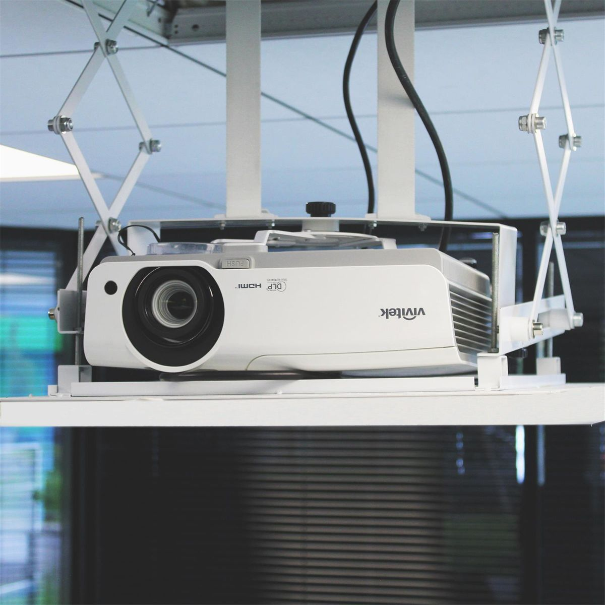 Un proyector blanco montado en el techo con cables negros y un logotipo de vivitek.