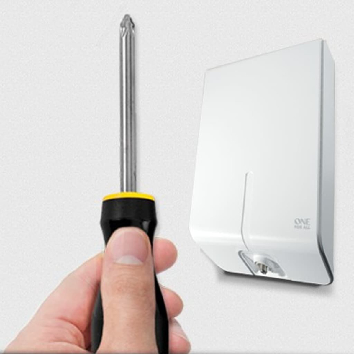 Una mano sostiene un destornillador junto a un dispositivo blanco rectangular montado en la pared.