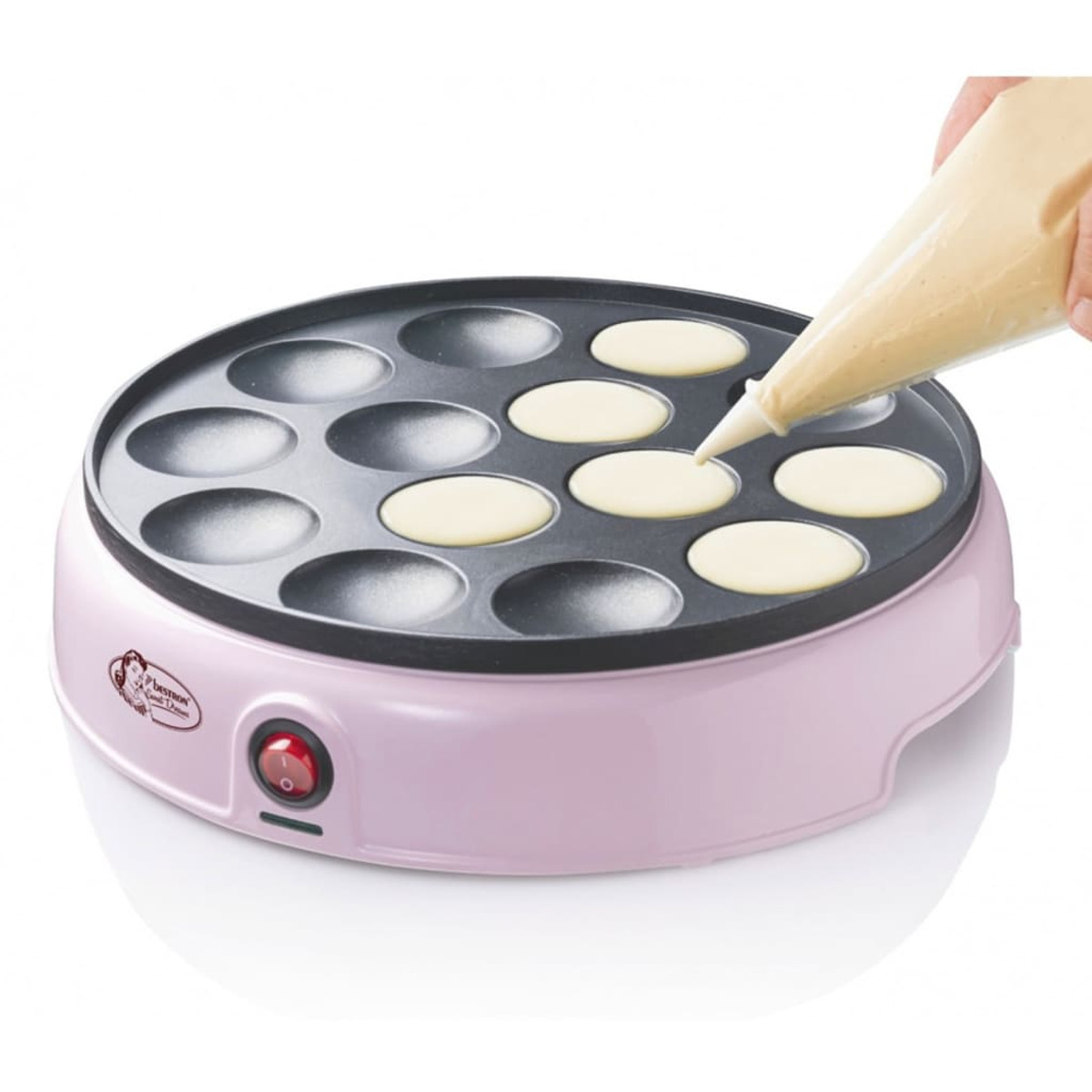 Różowa maszyna do naleśników z ciastem nakładanym na nią z worka do zdobienia.