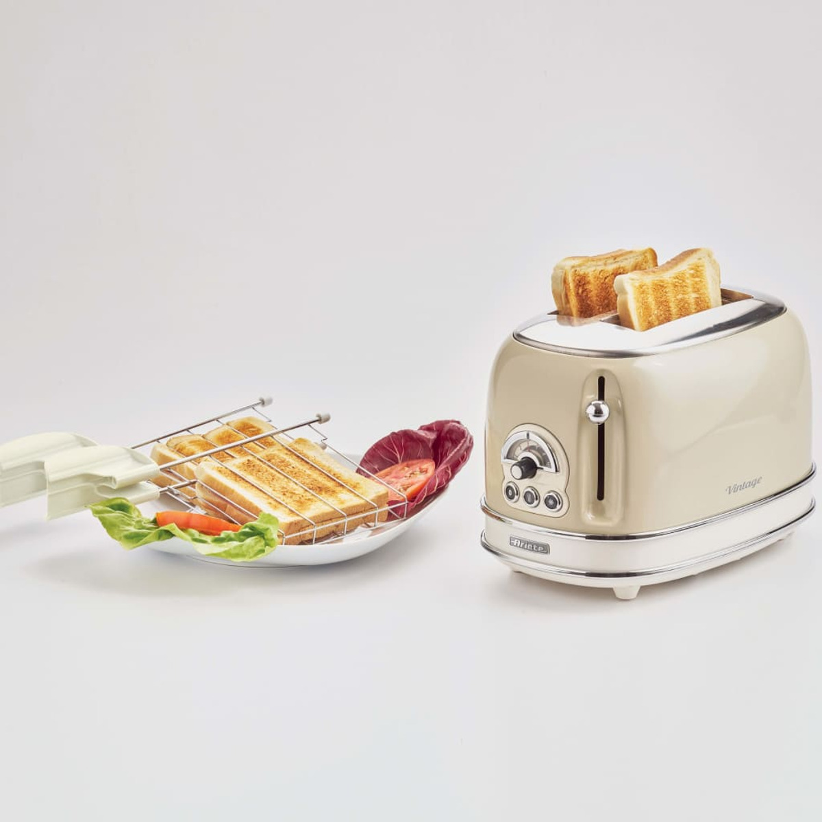 Een vintage beige broodrooster met toast en groenten op een bord. Witte achtergrond.