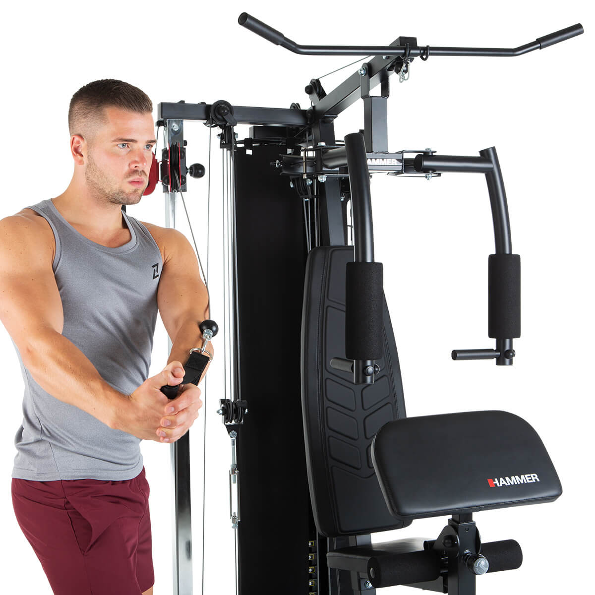 Mann benutzt eine Heimtrainingsmaschine. Er trägt ein graues Tanktop und rote Shorts.