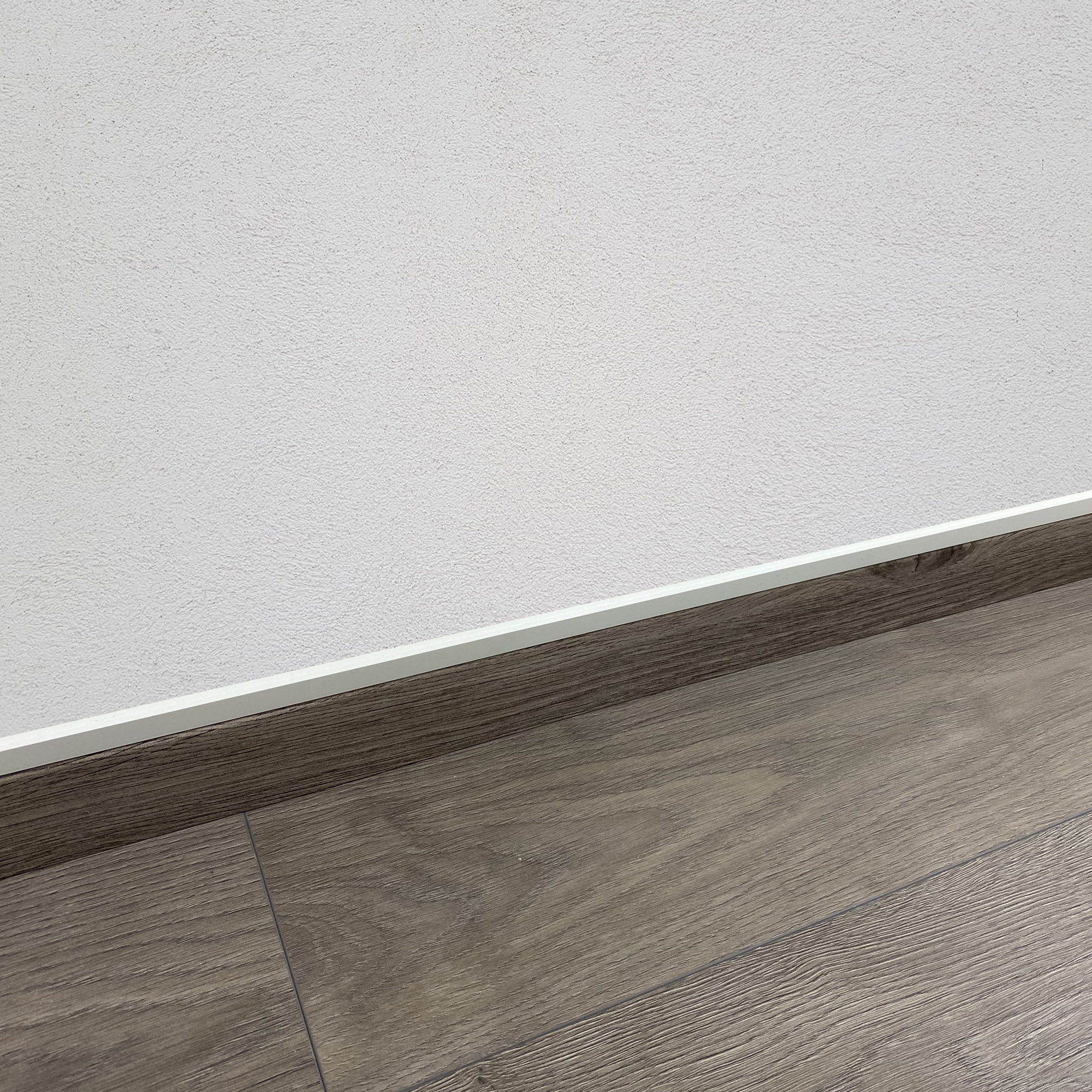 Holzboden und weiße Wand mit dünner weißer Linie.