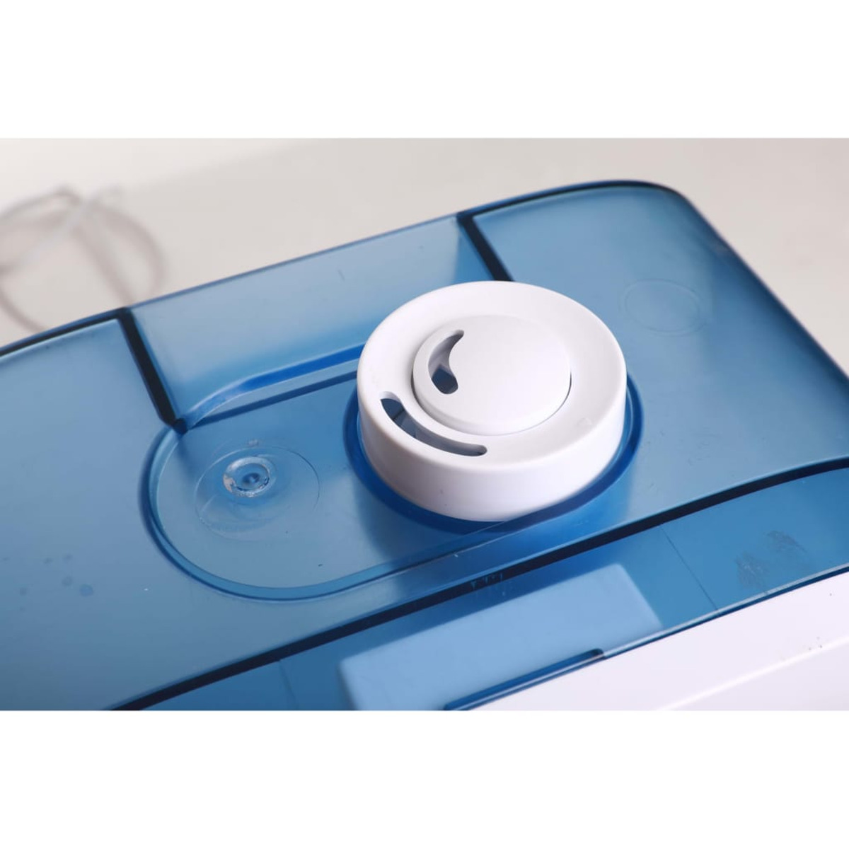 Biały nawilżacz powietrza z niebieskim zbiornikiem na wodę. Widok z góry.