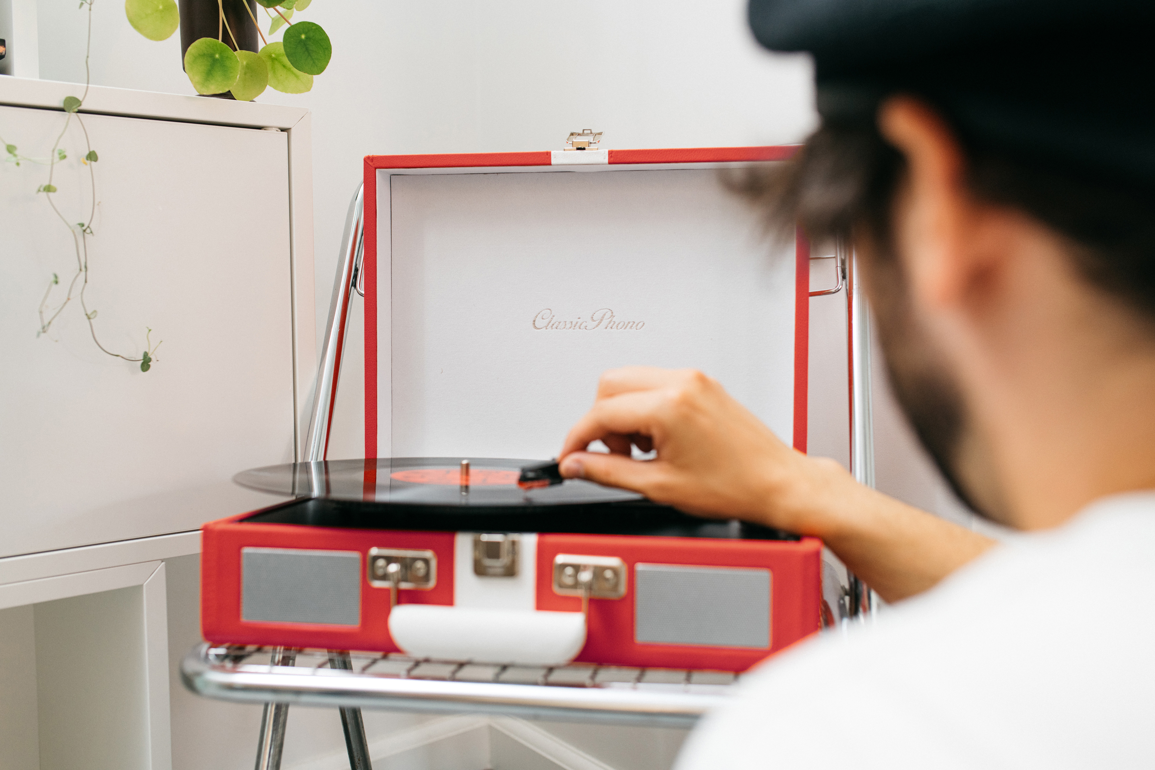 Una persona suona un disco in vinile su un giradischi retrò rosso. Il disco è nero, posizionato sul piatto.