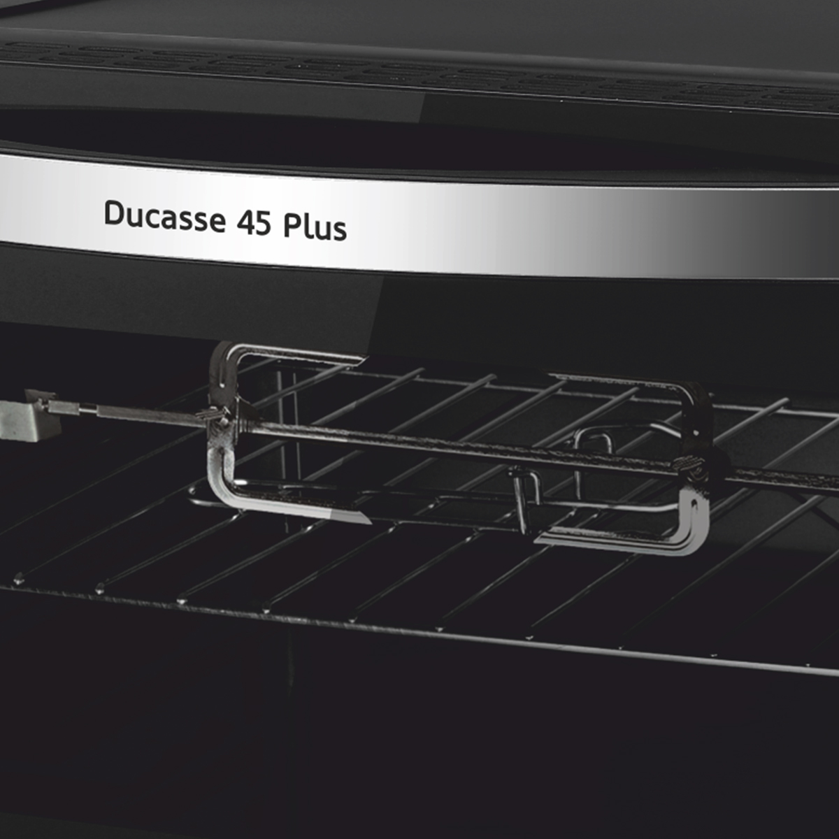 Primo piano dell'interno di un forno con girarrosto e scritta "Ducasse 45 Plus".