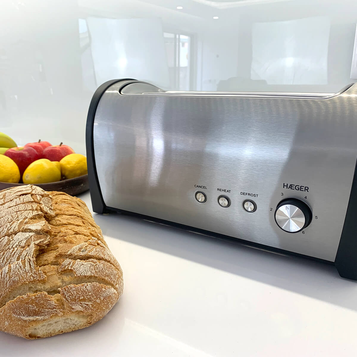 Toster z chlebem i owocami. Srebrny toster z panelem sterowania. Biała powierzchnia, jasne tło.