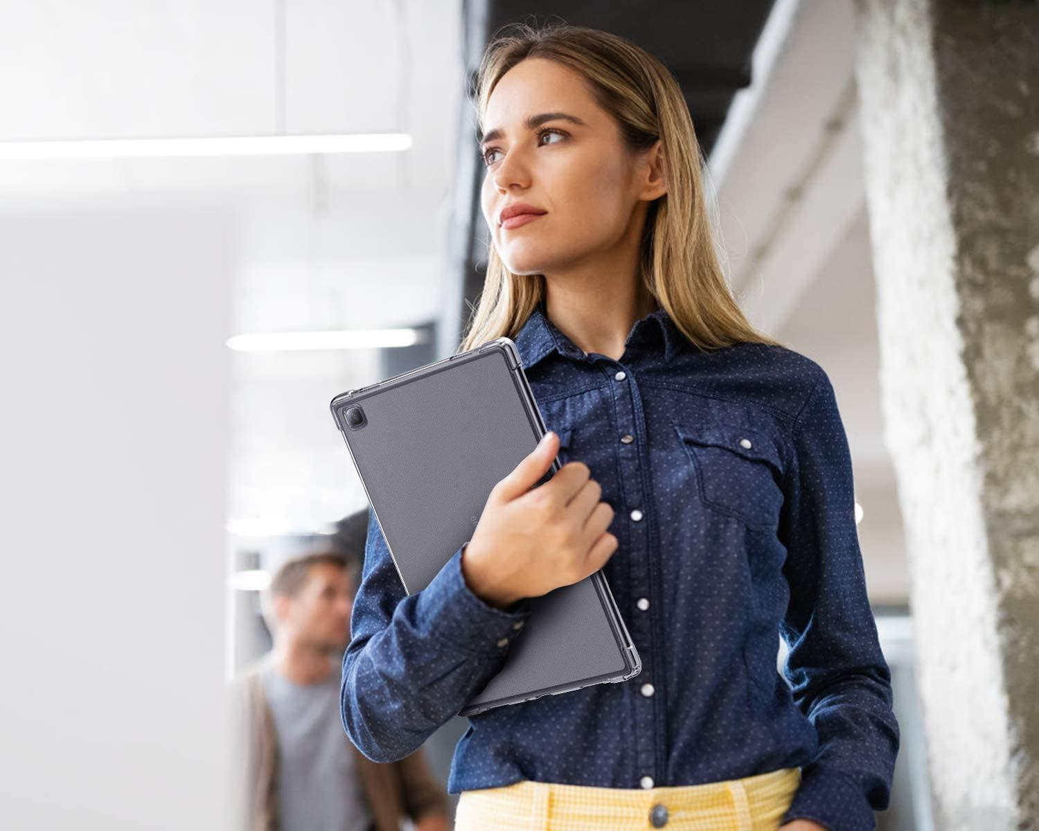 Eine Frau mit blonden Haaren, die ein Tablet hält, geht in einem Büro. Verschwommener Hintergrund.