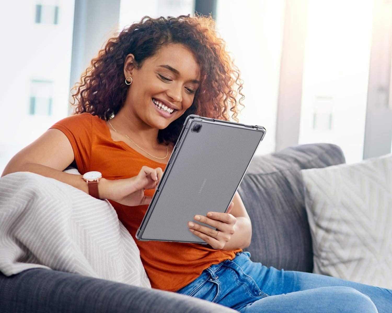 Eine Frau auf einem Sofa, die ein Tablet benutzt. Sie lächelt und hält das Tablet.
