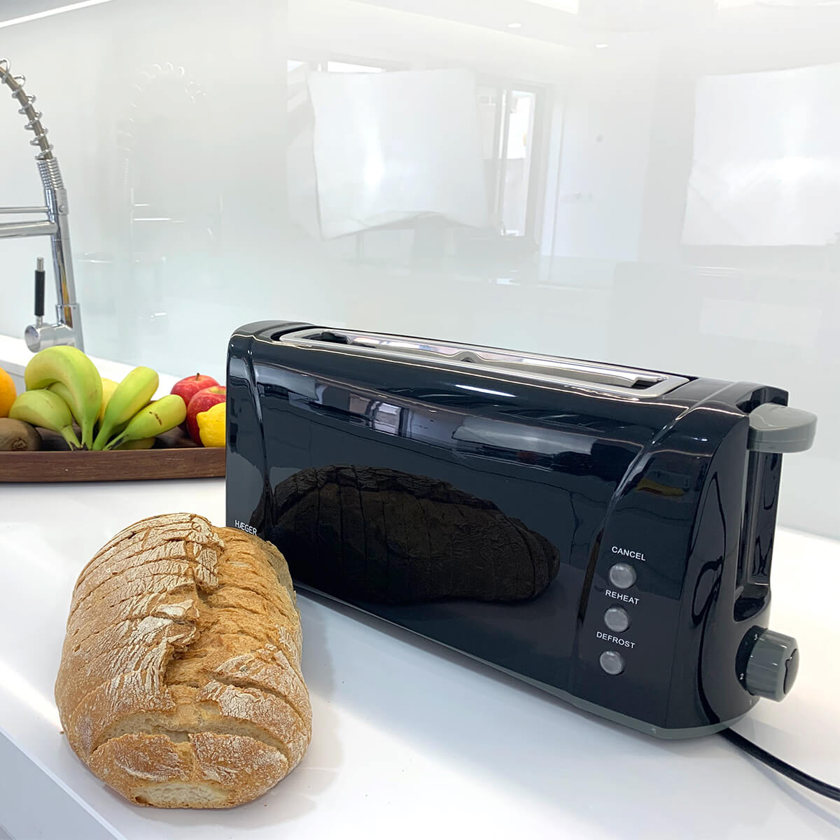 Czarny toster z chlebem, paterą owoców i białą ścianą. Scena na blacie.