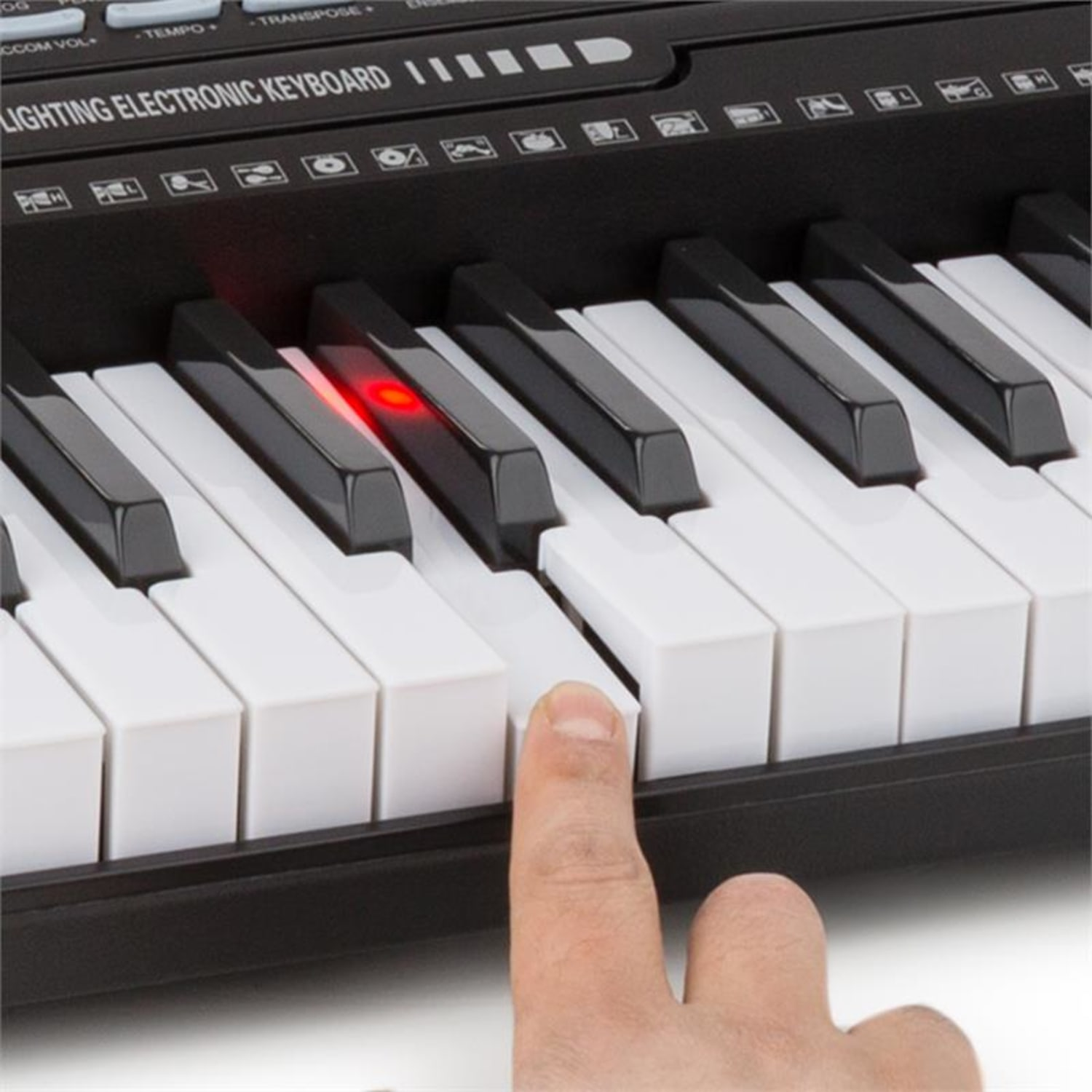 Ein Finger drückt eine Taste auf einer schwarzen elektronischen Tastatur. Eine Taste leuchtet rot.