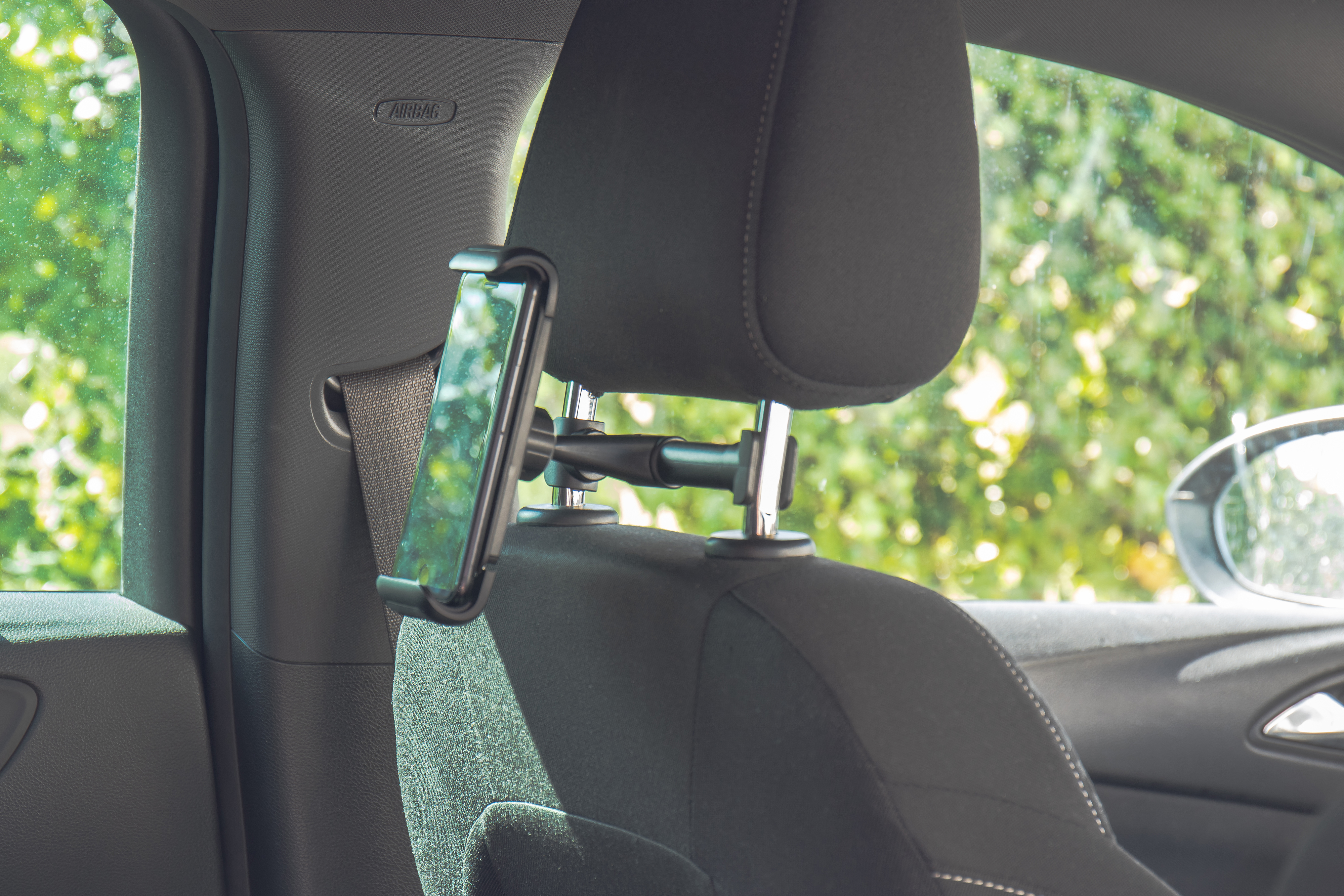 Autokopfstützen-Telefonhalterung mit befestigtem Telefon, im Innenraum eines Autos.