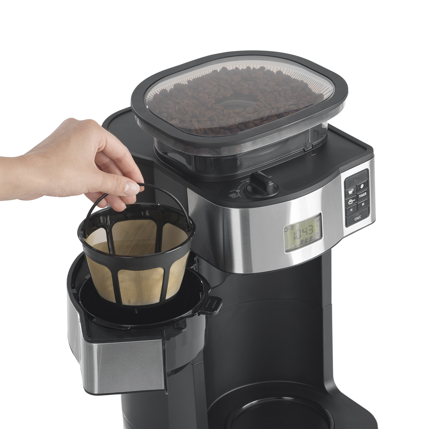 La mano di una persona che tiene un cestello filtro in una macchina da caffè con chicchi di caffè in un contenitore sopra.