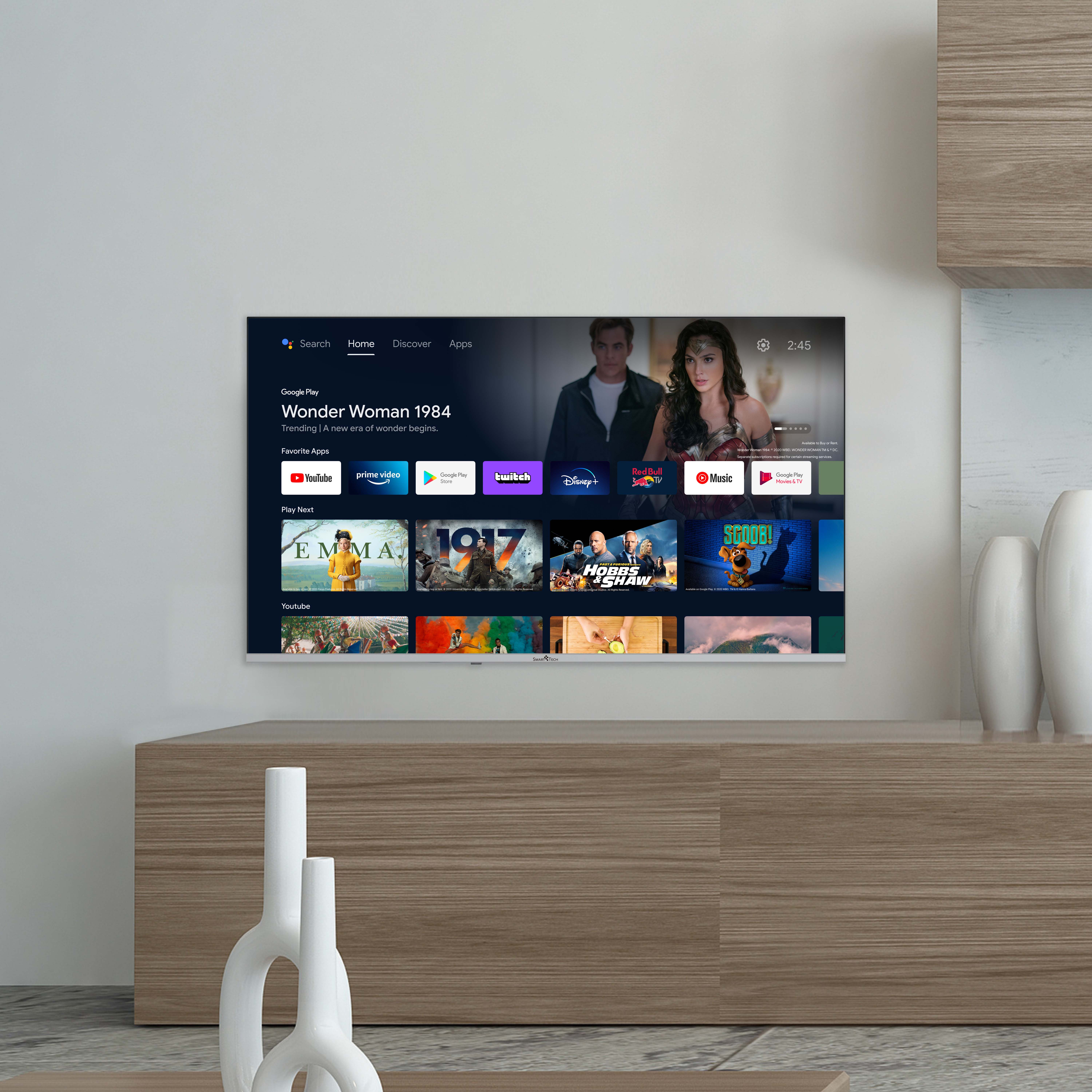 Telewizor wyświetla film, zamontowany na drewnianej szafce, białe tło.