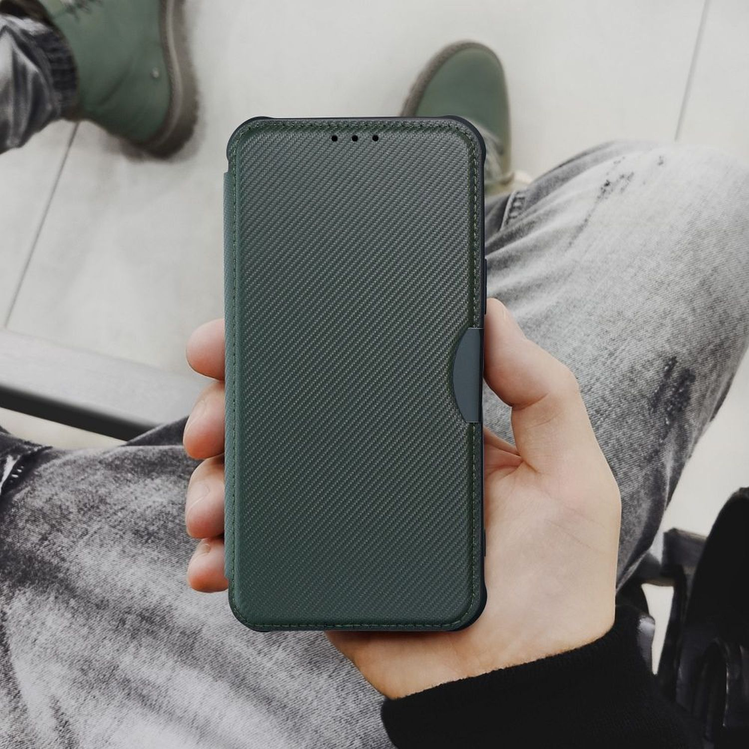Eine Person hält eine grüne Handyhülle. Die Hülle ist offen und zeigt das Telefon im Inneren.