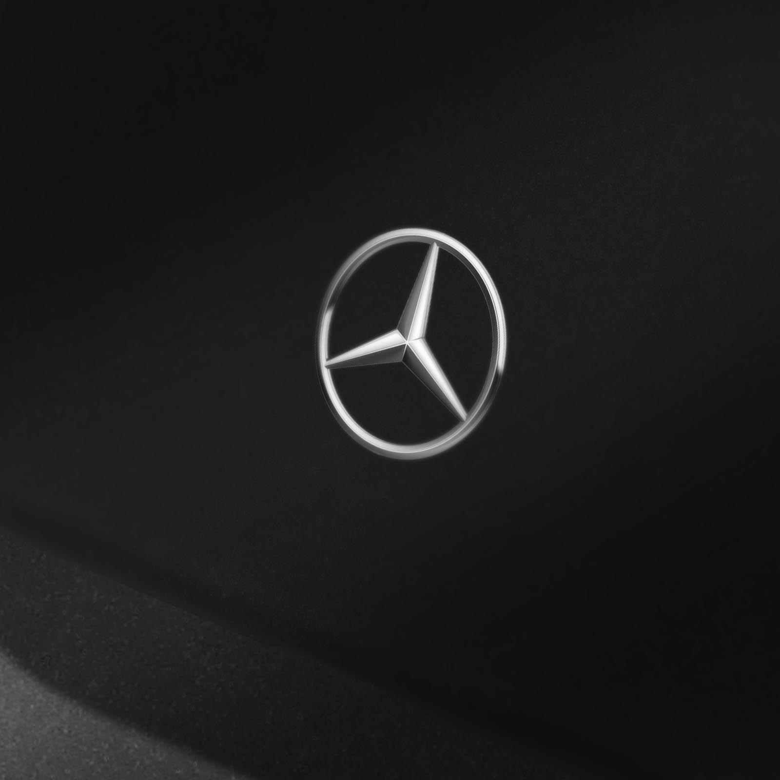 Silbernes Mercedes-Benz Logo auf schwarzem Hintergrund. Das Logo ist ein dreizackiger Stern in einem Kreis.