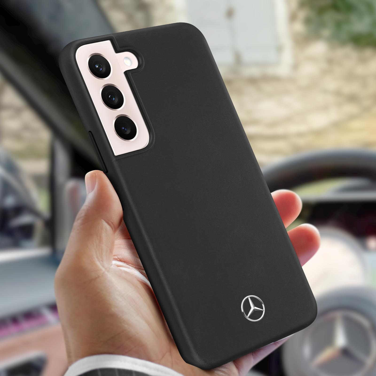 Eine Hand hält eine schwarze Handyhülle mit dem Mercedes-Benz-Logo.