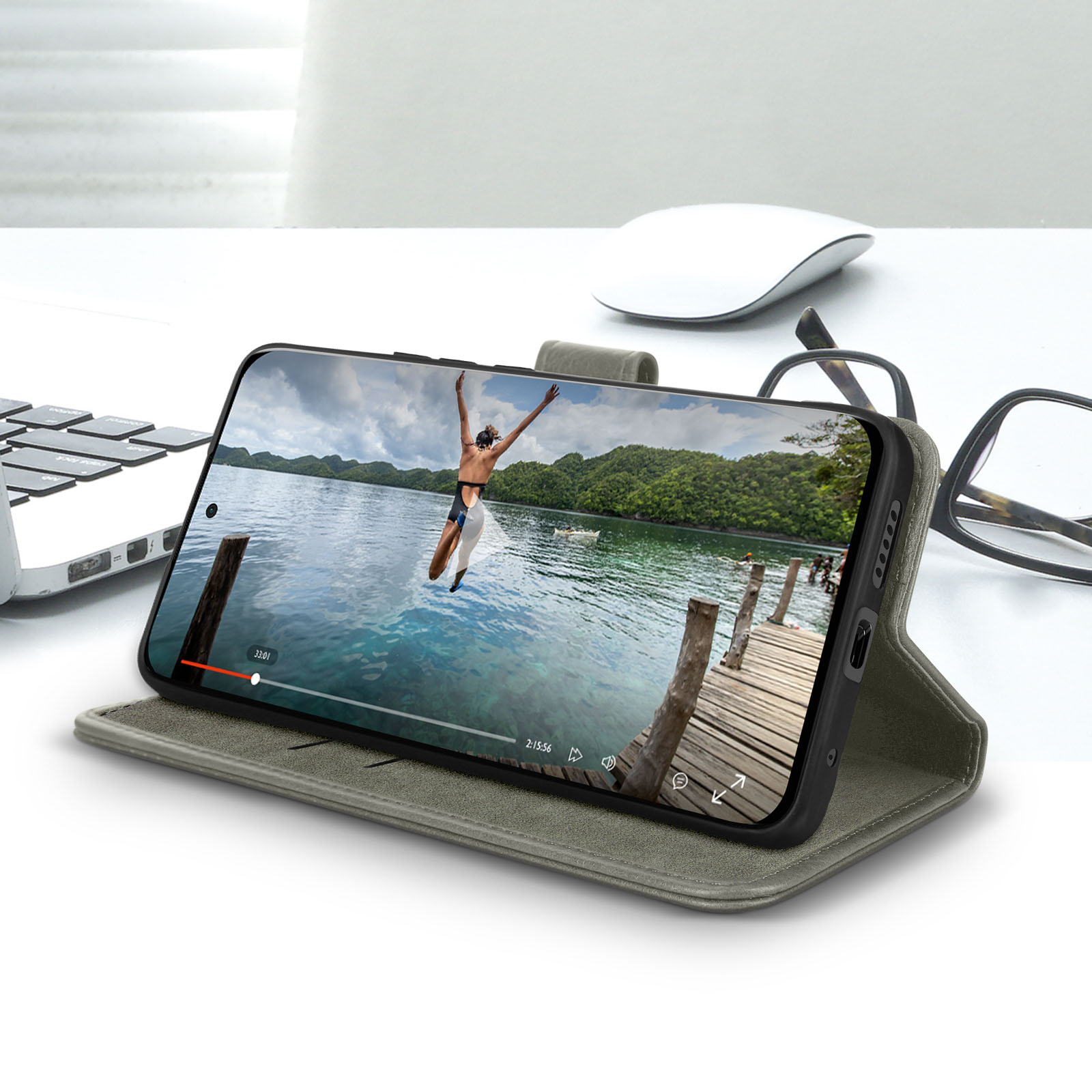 Telefon auf einer Hülle, zeigt ein Video. Es liegt auf einem Tisch mit Brille und Maus.