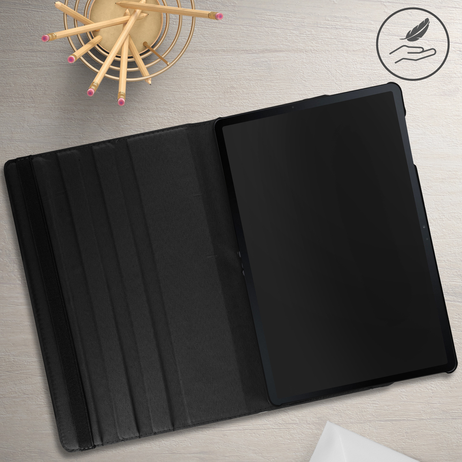 Tablet in una custodia nera su un tavolo di legno. Matite in un portamatite dorato.