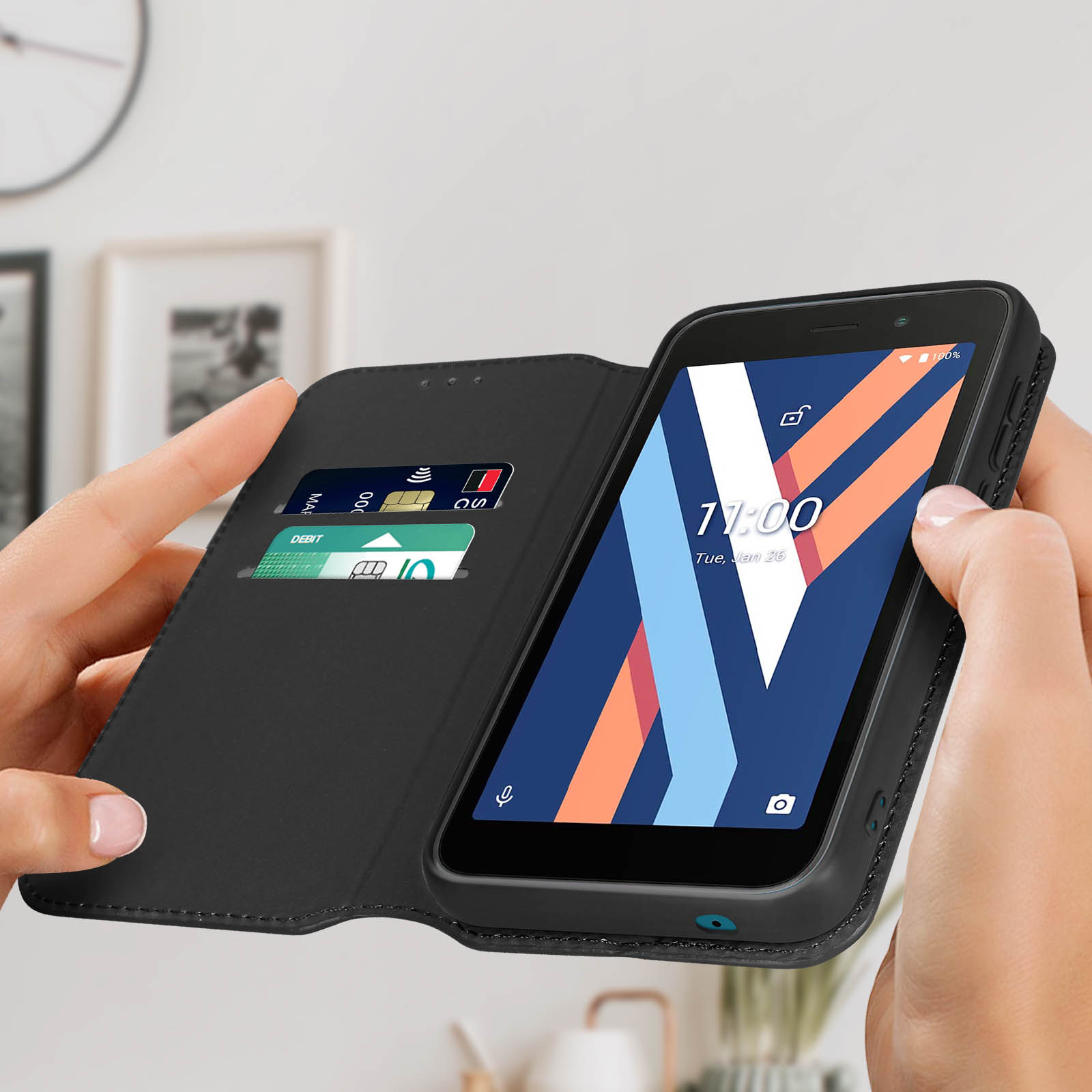 Mains tenant un téléphone dans un étui noir, affichant une horloge colorée. L'étui a des fentes pour cartes.
